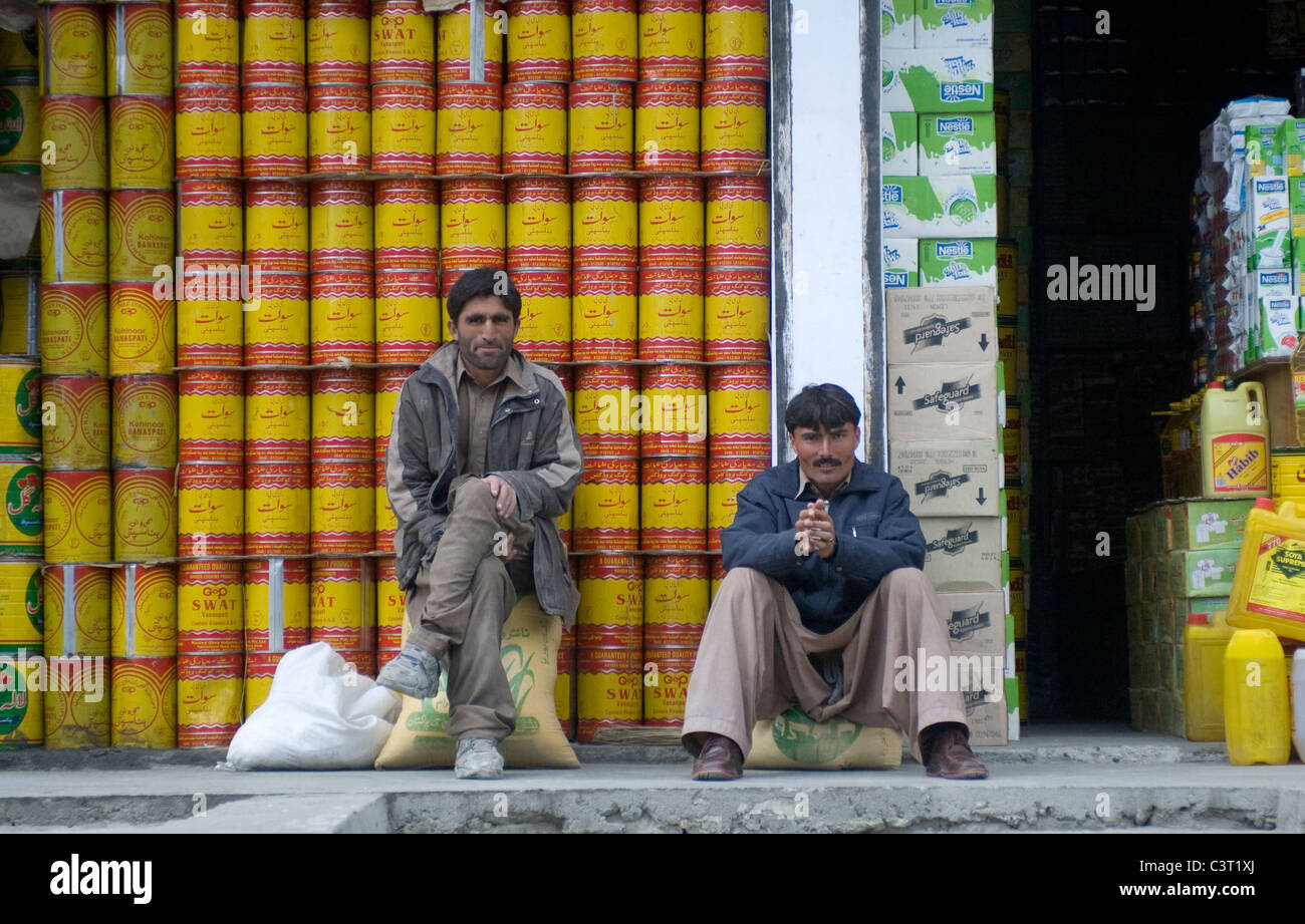 Men sit in front of a shop on the Karakoram Highway. Stock Photo