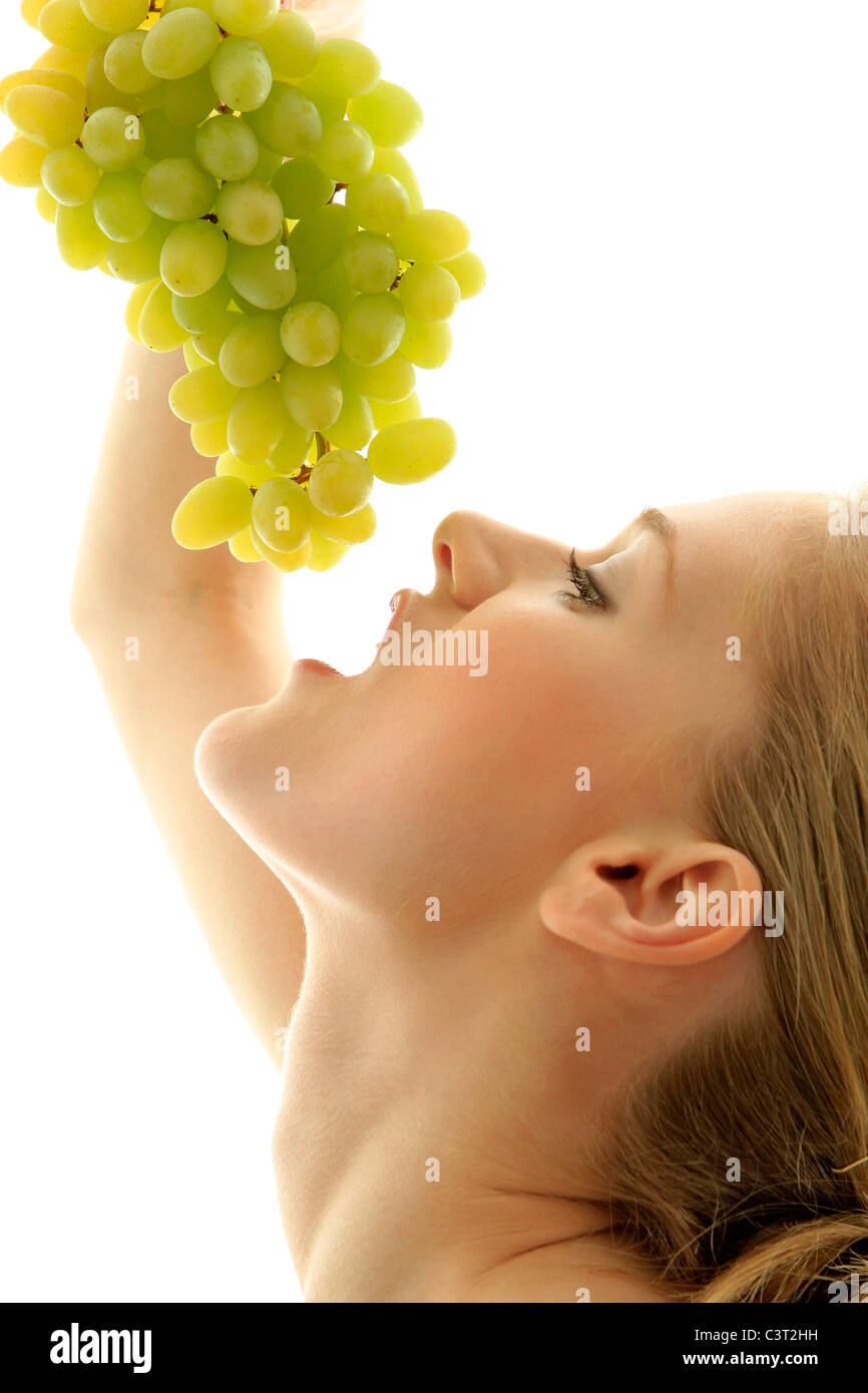 Happy young woman eating grapes Stock Photo