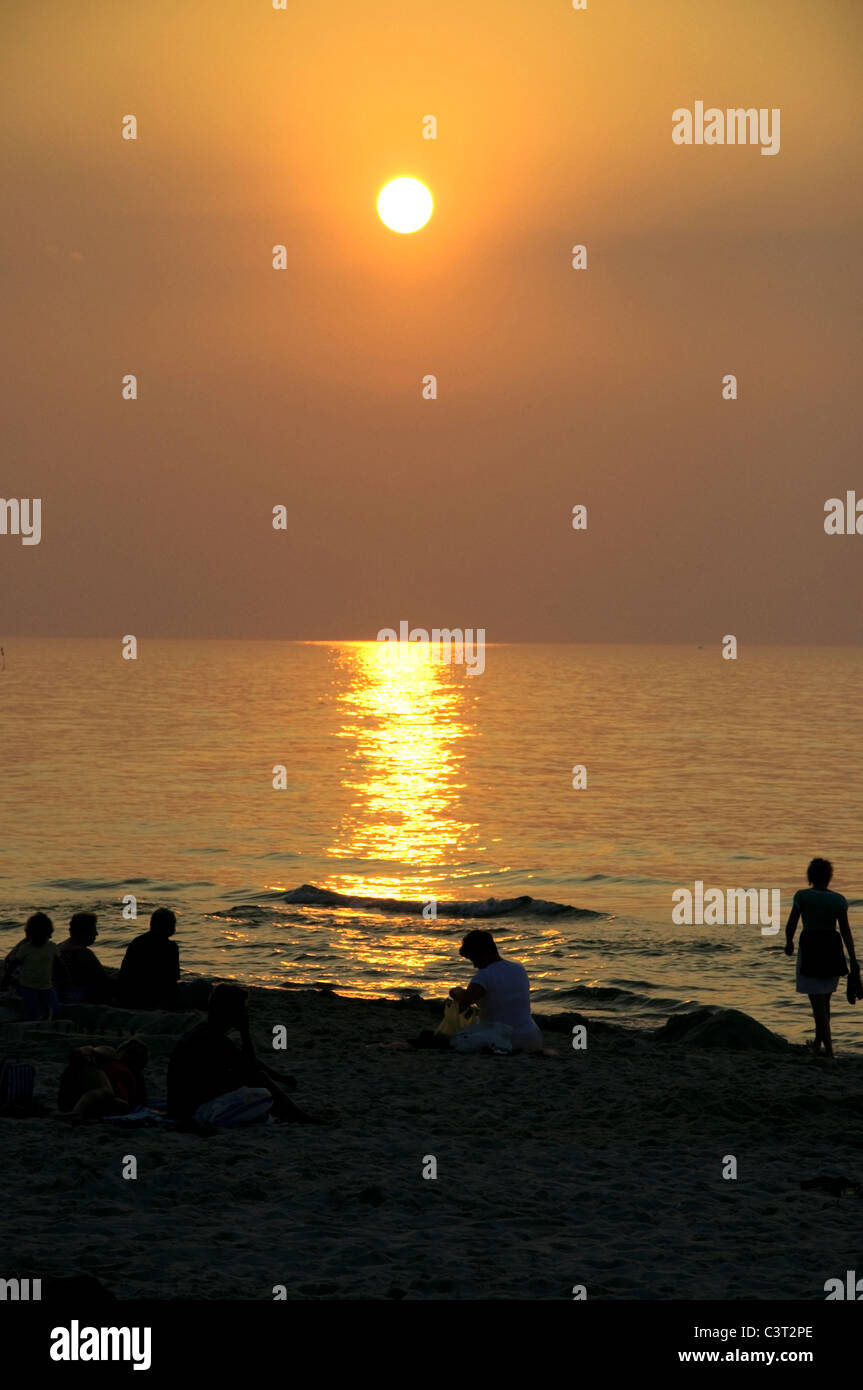 Group of people is looking at the sunset at the seaside Stock Photo
