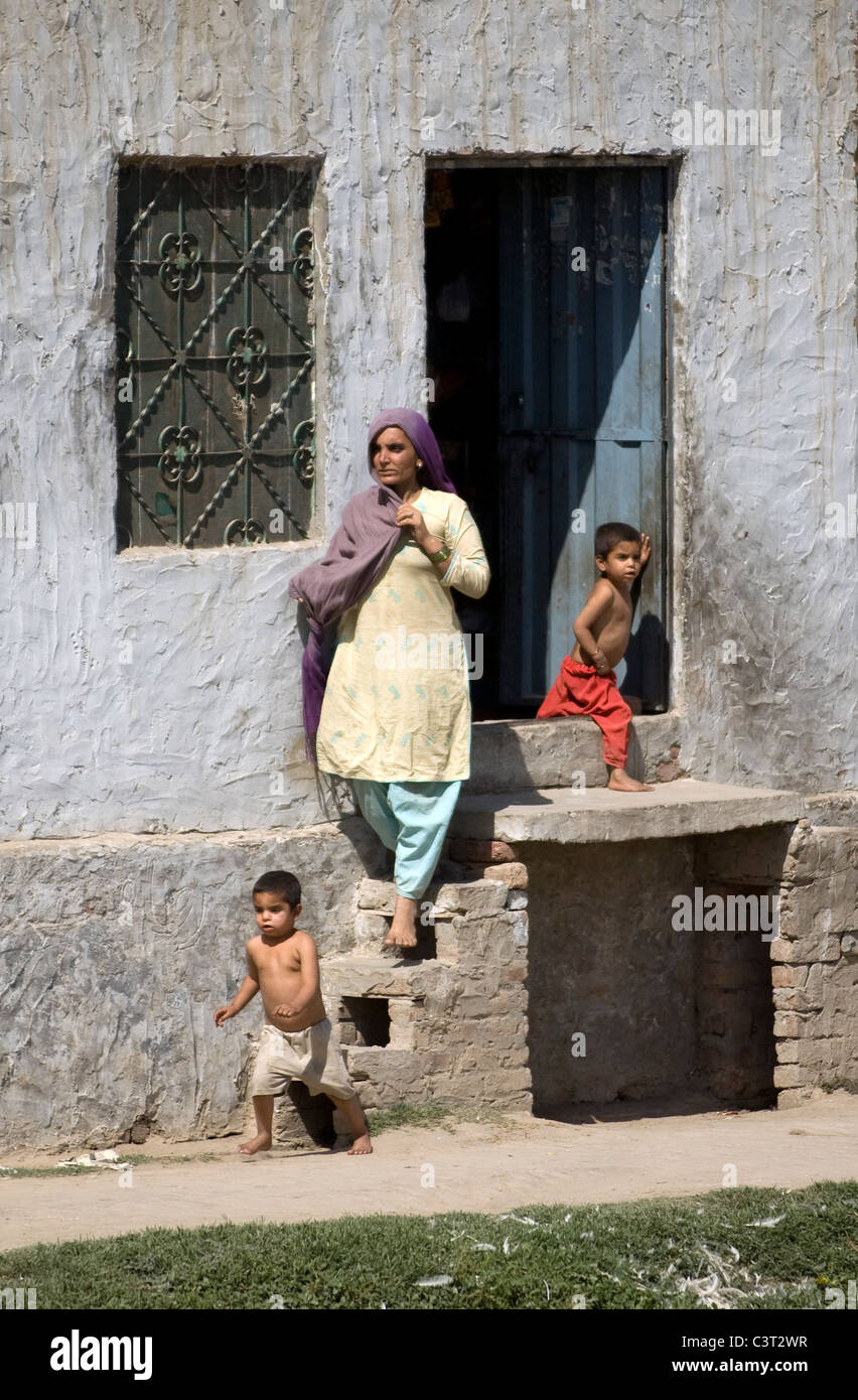 Woman and children exit a home near Gujrat. Stock Photo