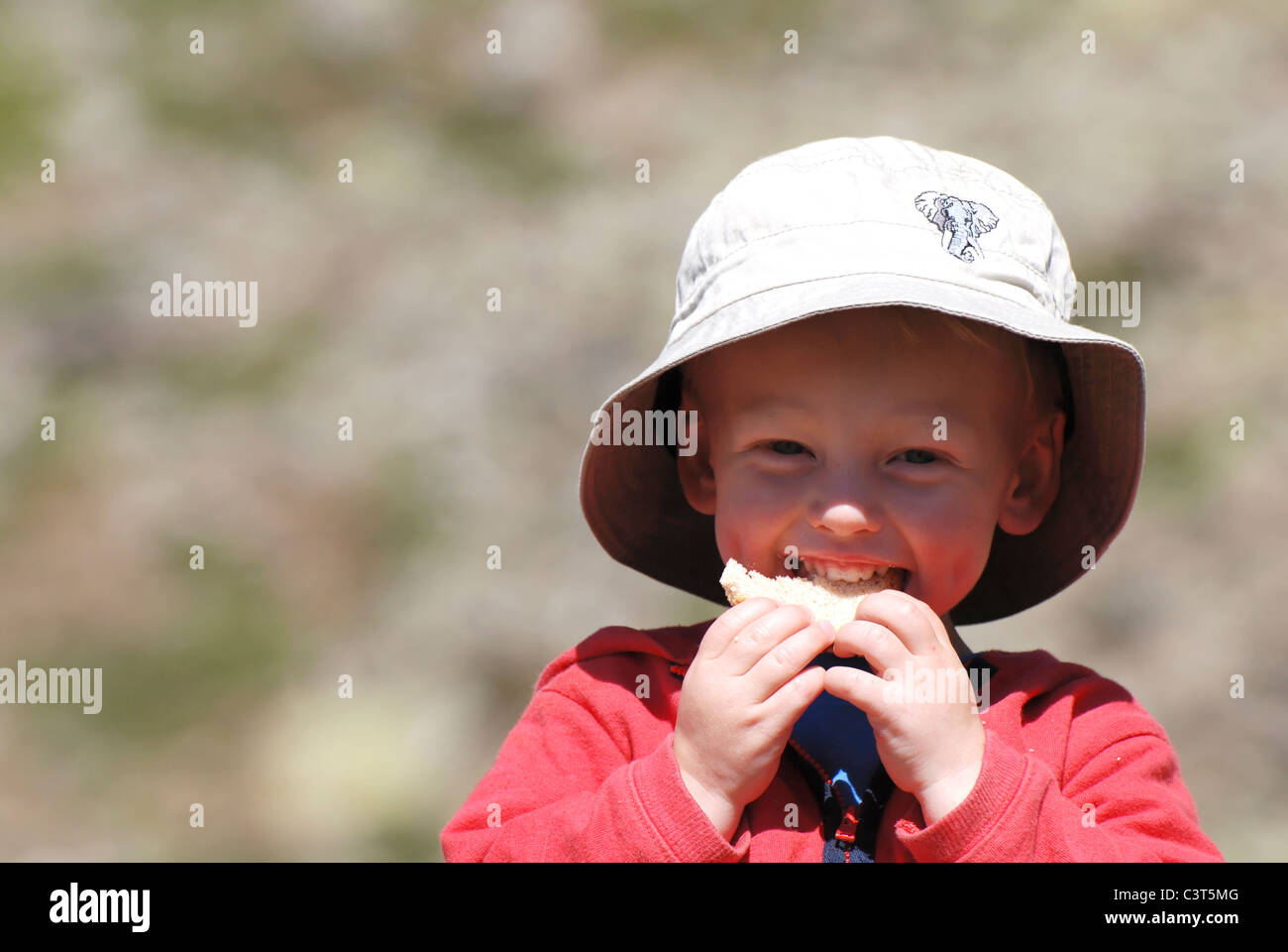 A young boy sat enjoying a drink and a picnic at Kreuzboden in the Saas valley, Switzerland. Stock Photo