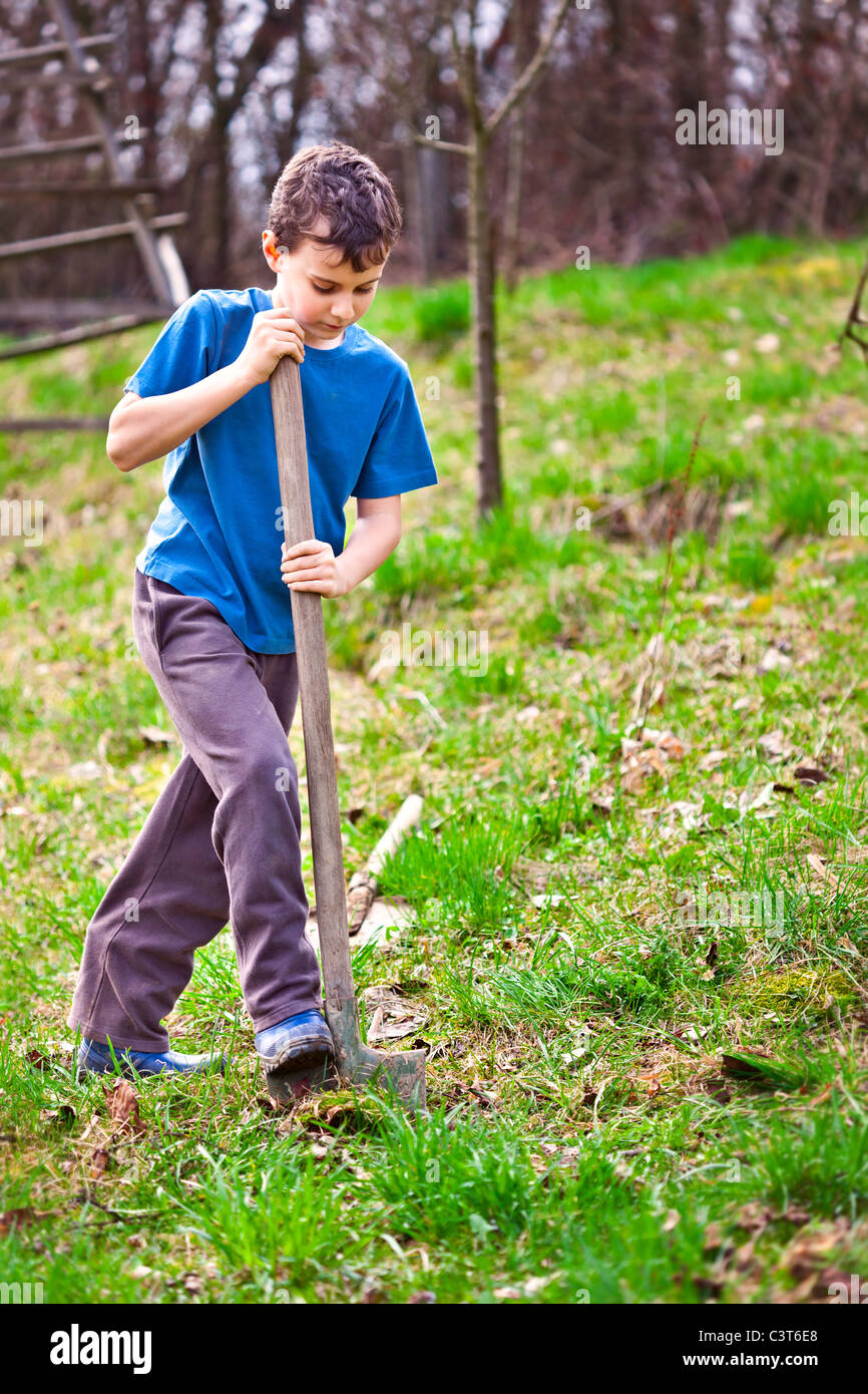 Farm boy with a shovel digging in the garden Stock Photo - Alamy