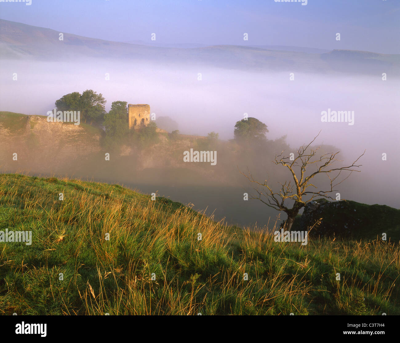 Peveril Castle shrouded in mist, viewed from above Cave Dale in Castleton Stock Photo