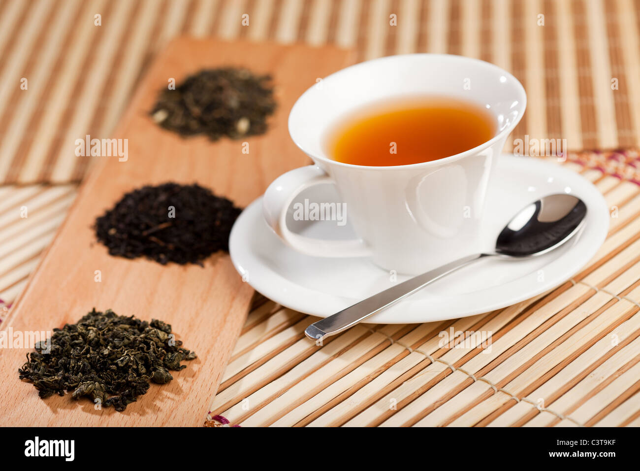 A cup of tea near three piles of various kinds of tea Stock Photo Alamy