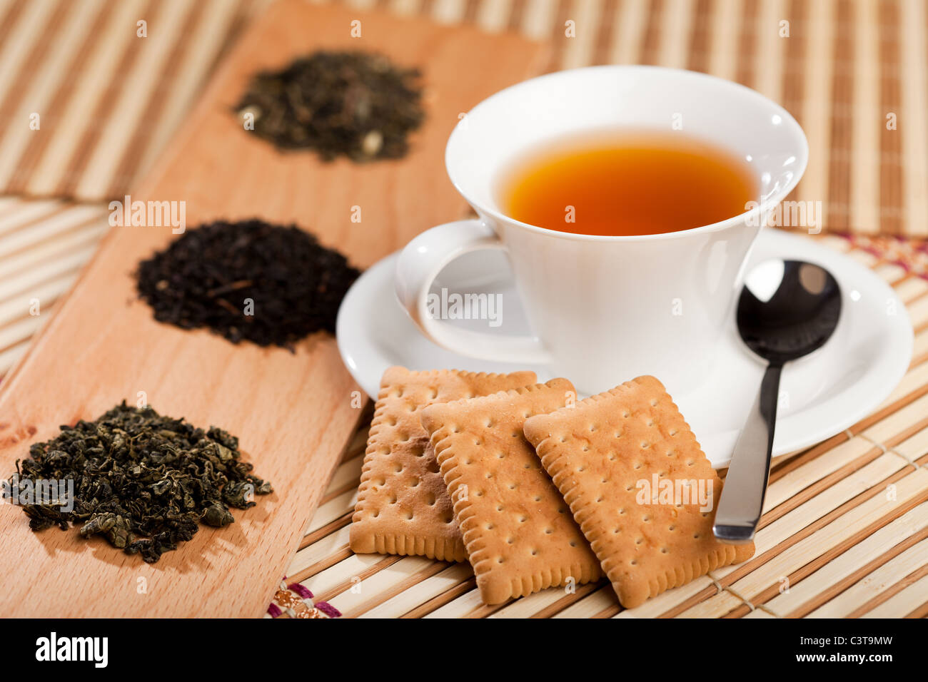 A cup of tea near three piles of various kinds of tea Stock Photo Alamy