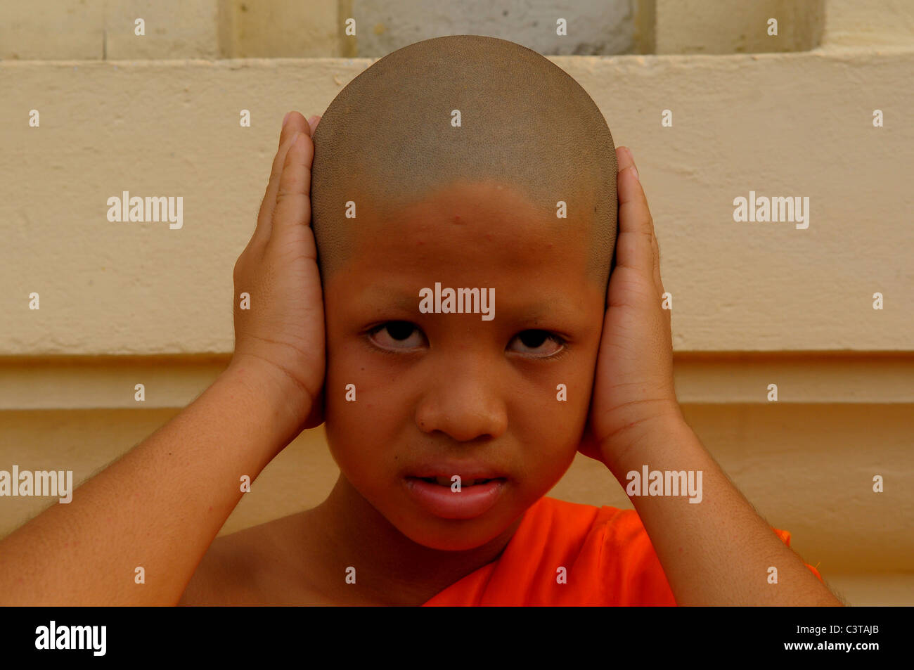 HEAR NO EVIL, Young novice doing the three wise monkeys,proverbial principle  ,Wat Santithammaram, Bangkok, thailand Stock Photo