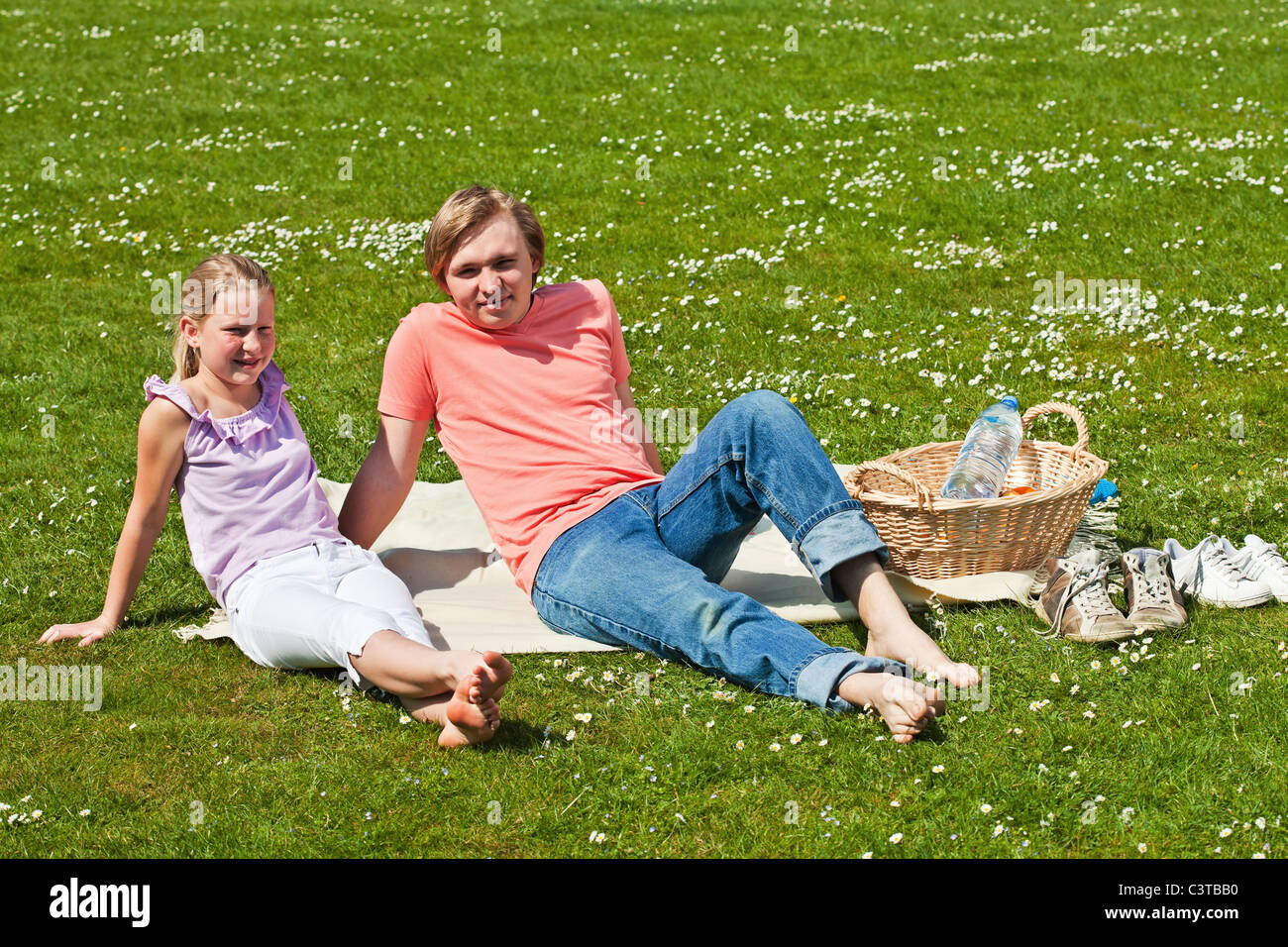 Teenager brother and sister having a picnic in the park in a bright ...