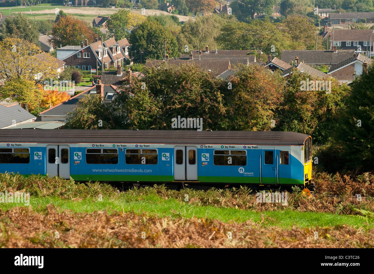 A train in Network West Midlands livery travelling through the English countryside. Stock Photo