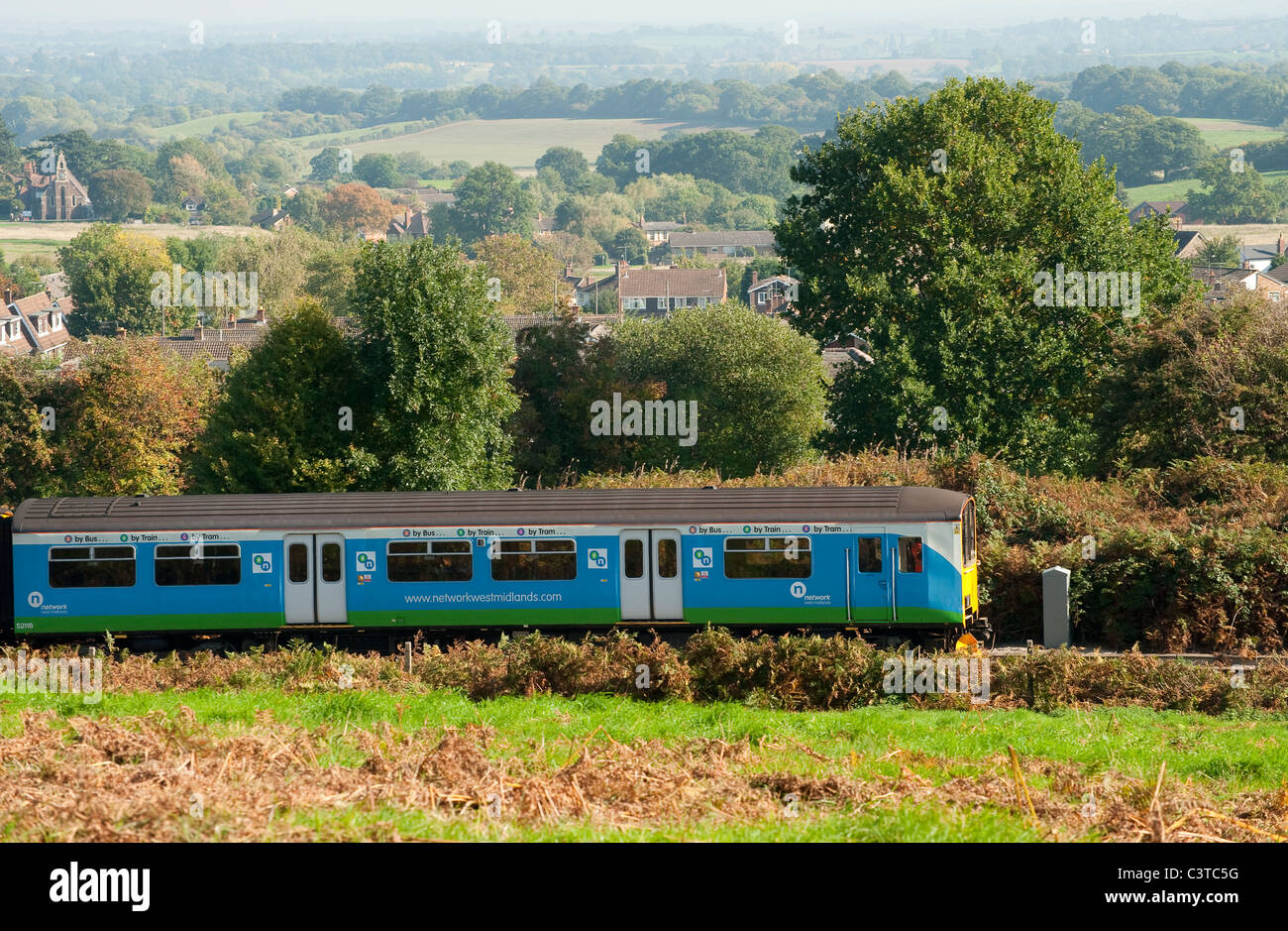 A train in Network West Midlands livery travelling through the English countryside. Stock Photo