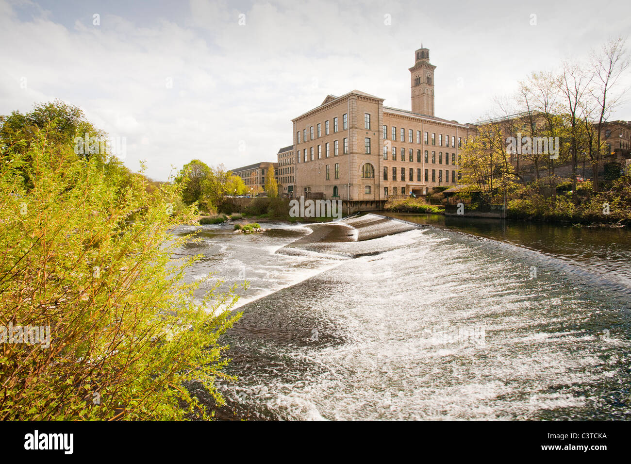 Salts mill in Saltaire, Yorkshire, UK and a weir on the River Aire. The mill was opened in 1853 by Titus Salt to process alpaca Stock Photo