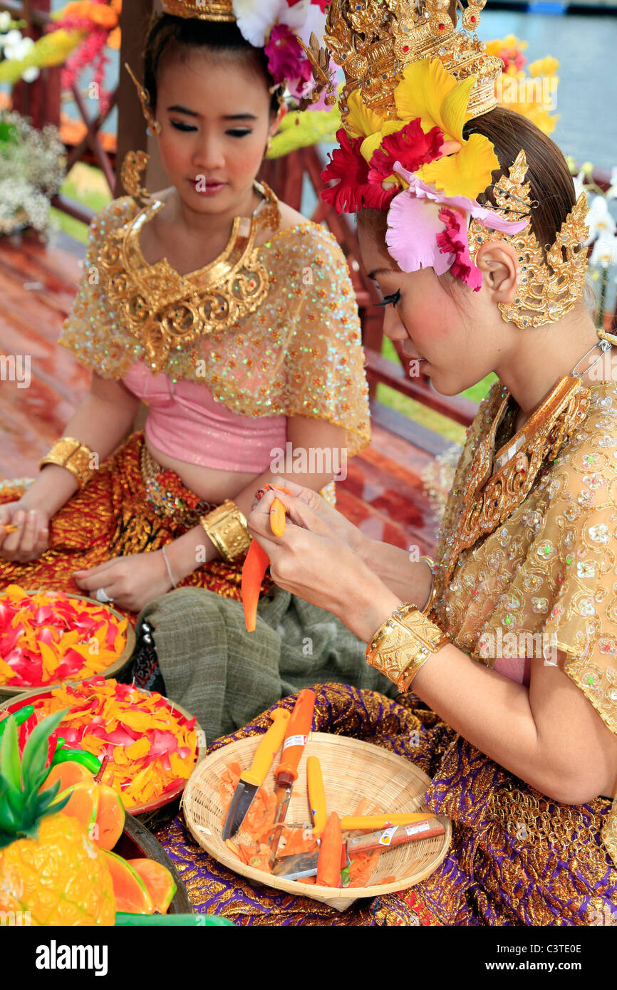 Traditionally dressed Thai ladies decorating carved vegetables Stock Photo