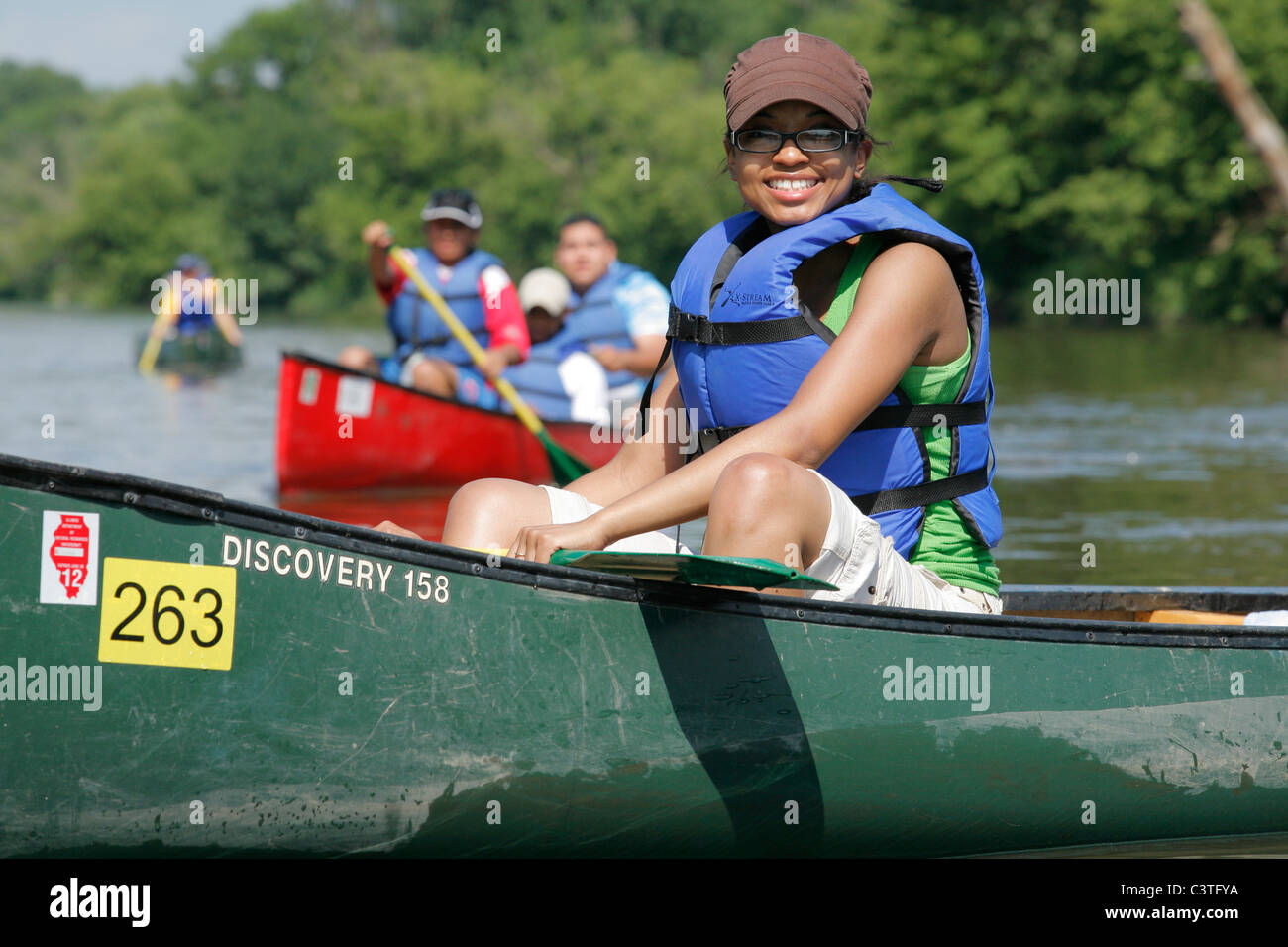 Young multi ethnic adults in canoes paddle on the Fox River in Yorkville Illinois USA Stock Photo