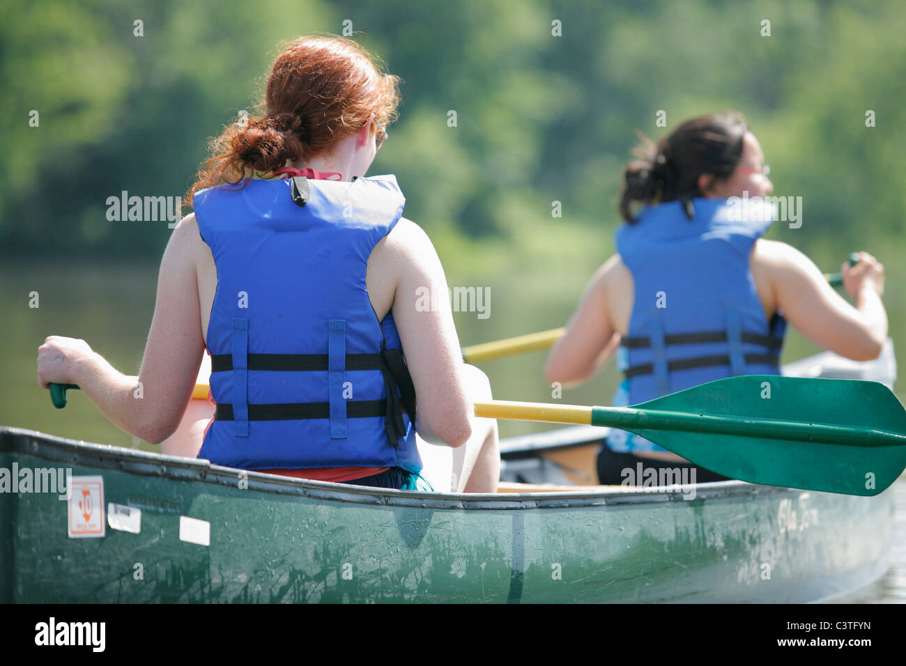 Two young multi ethnic adult women in a canoe paddle on the Fox River