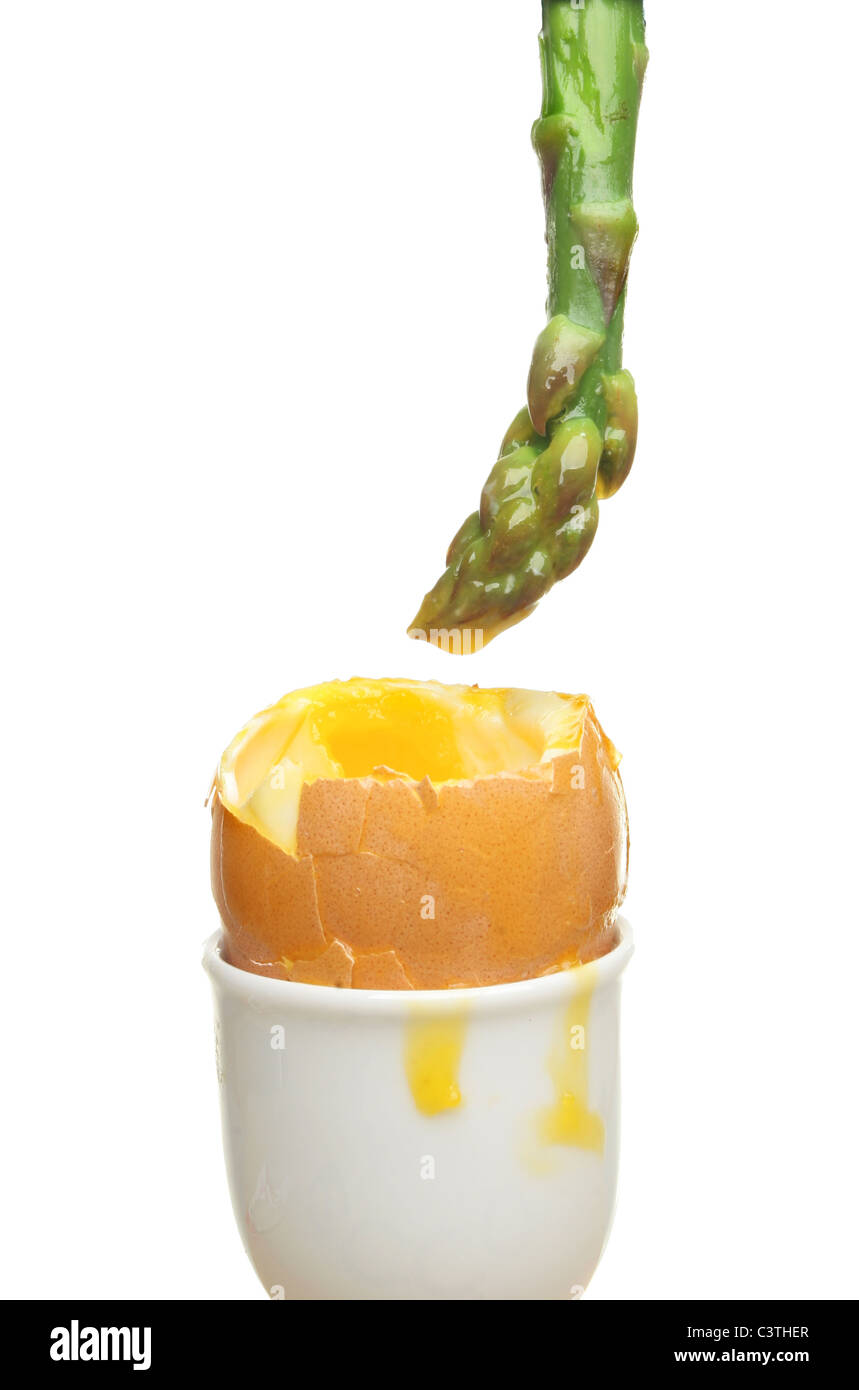 Asparagus spear dipped in the yolk of a soft boiled egg against white Stock Photo
