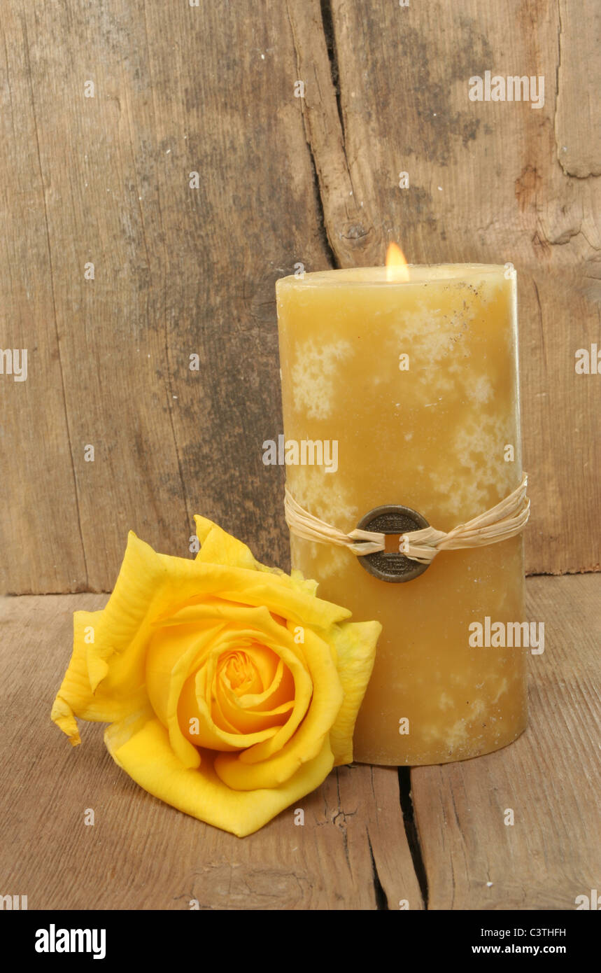 Burning Feng Shui candle and yellow rose on a background of old weathered wood Stock Photo