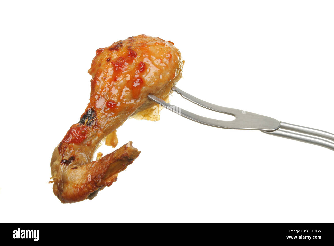 Barbecued chicken leg with tomato relish on a barbecue fork isolated against white Stock Photo