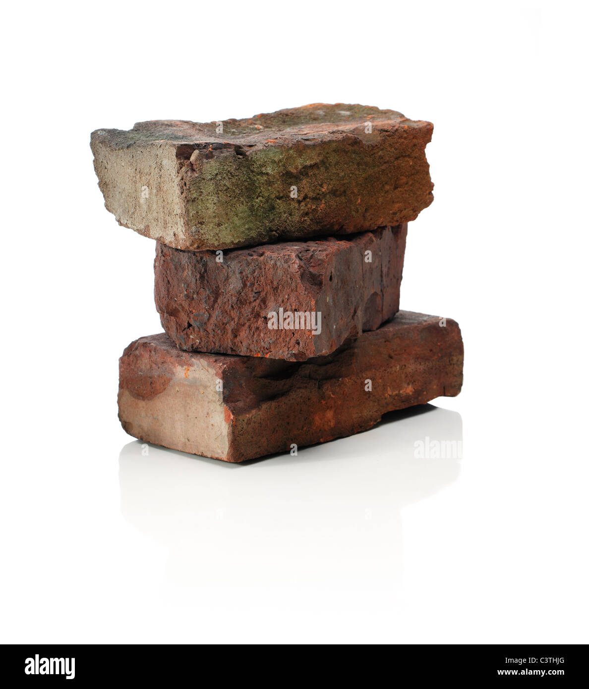 Three old bricks, stacked on a reflective background Stock Photo