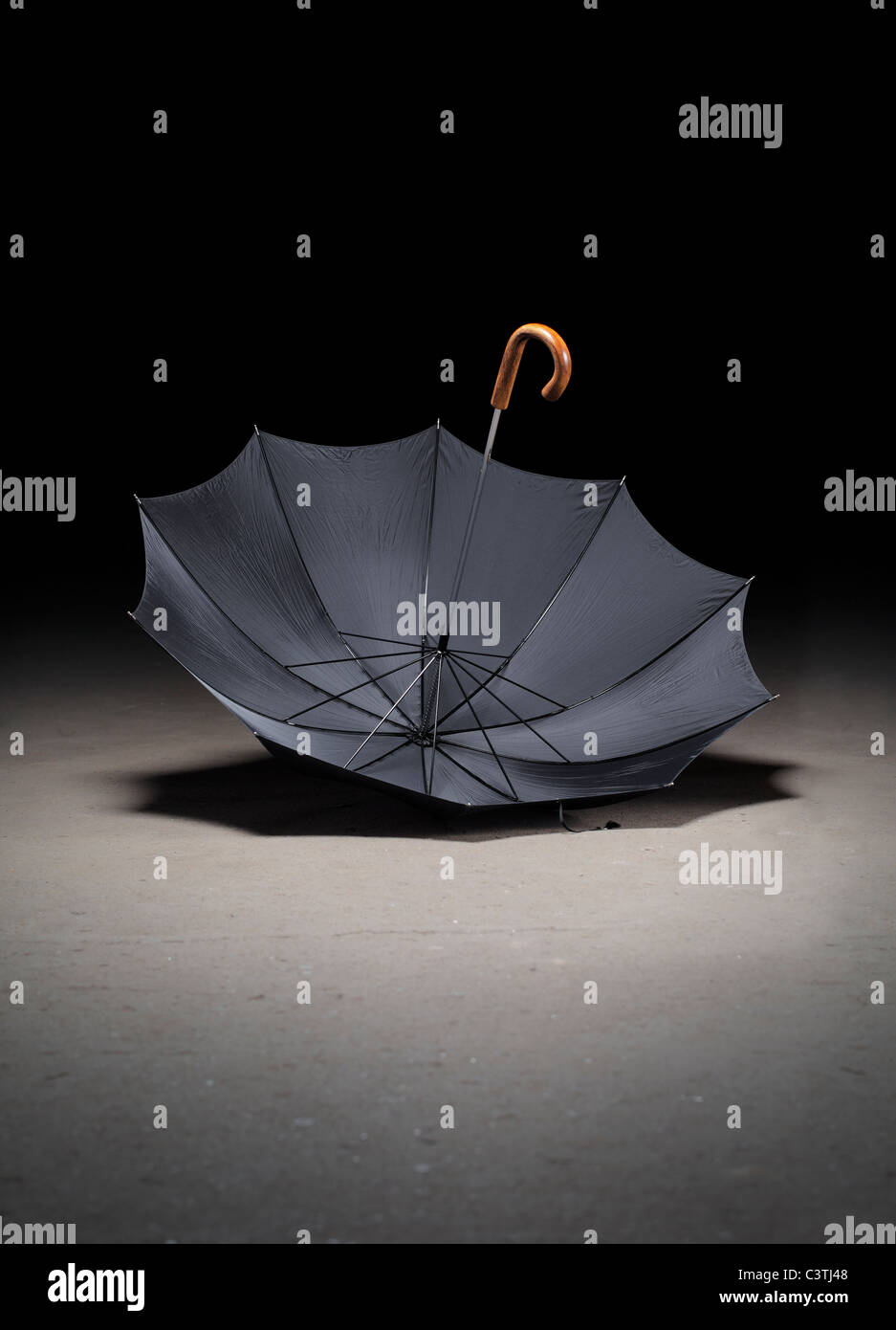 Old black umbrella upside down on dirty concrete floor Stock Photo