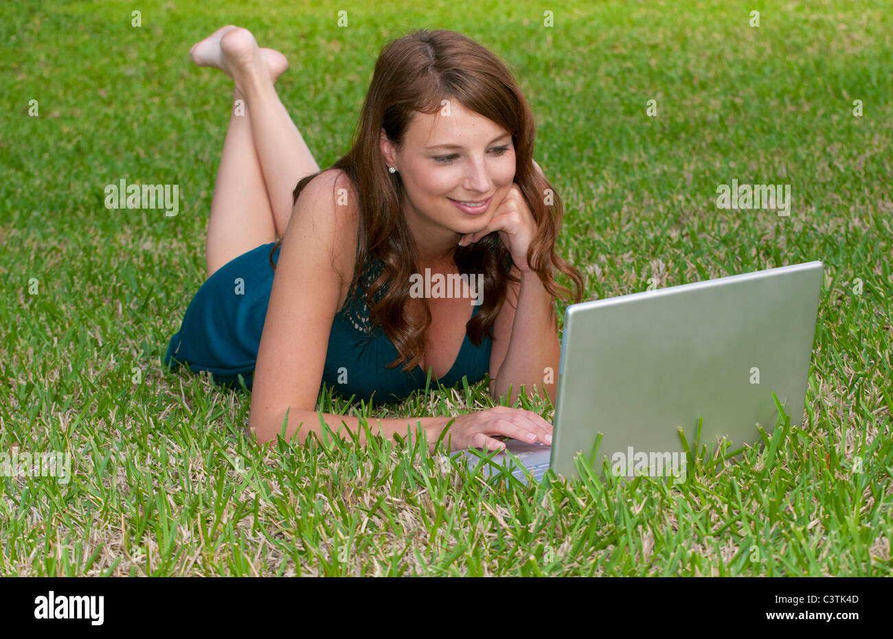 Young girl laying in yard emailing and searching web having fun with Facebook with friends Stock Photo