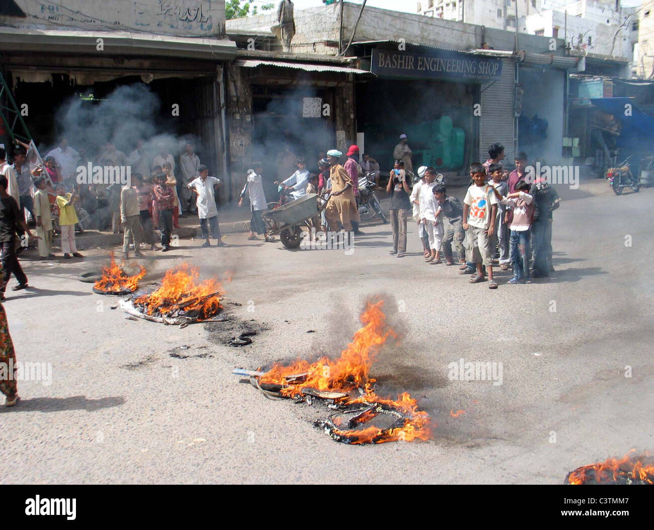People look at burning tyres and garbage which were set ablaze by angry