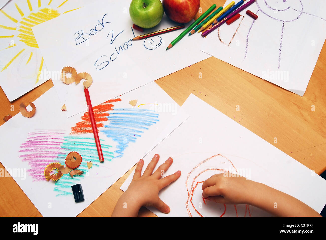 Little hands drawing between school supplies and apples Stock Photo Alamy