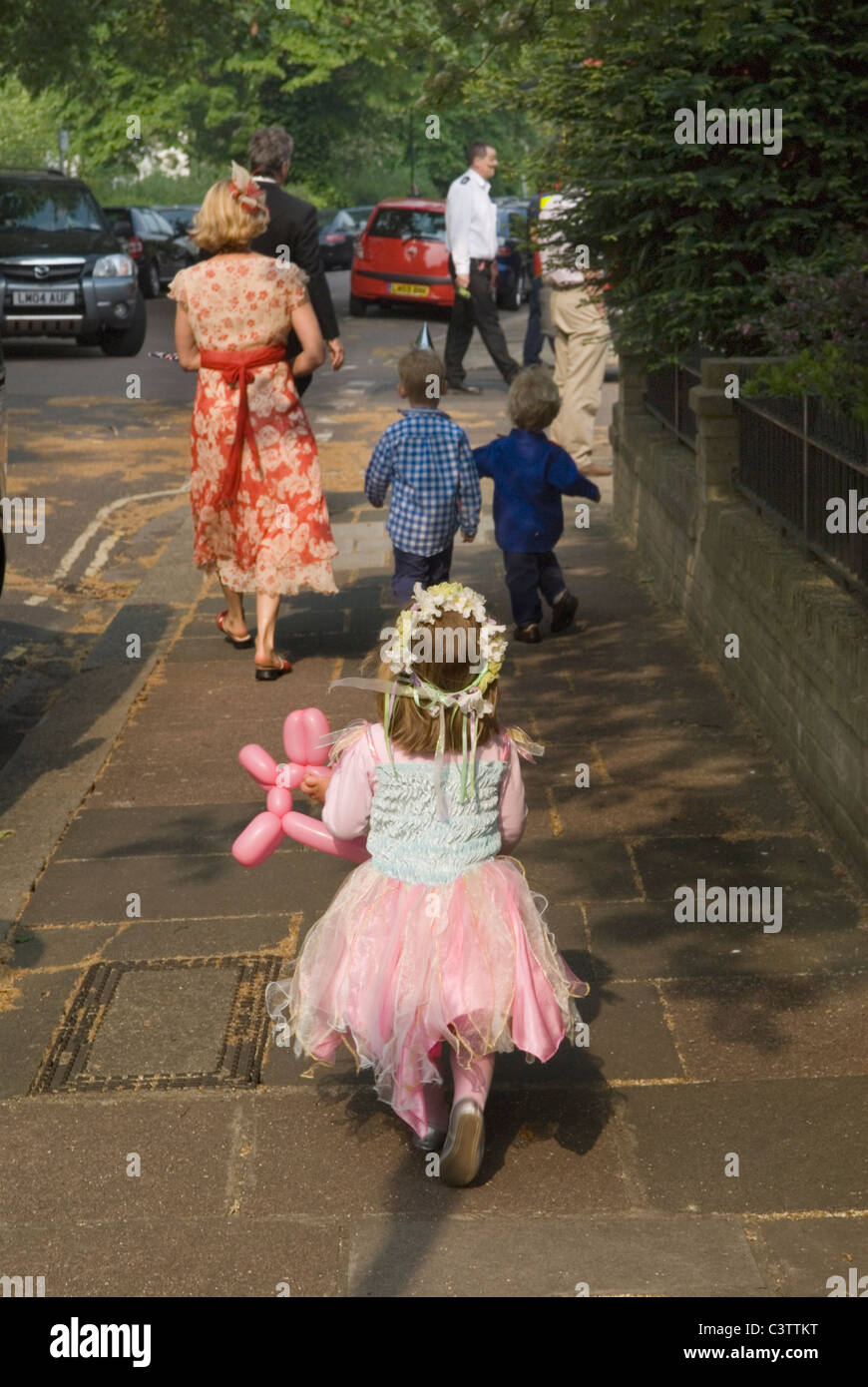 Pink for Little Girls. Young girl dressing up  going to a party with mother and brothers London 2011 2010s UK HOMER SYKES Stock Photo
