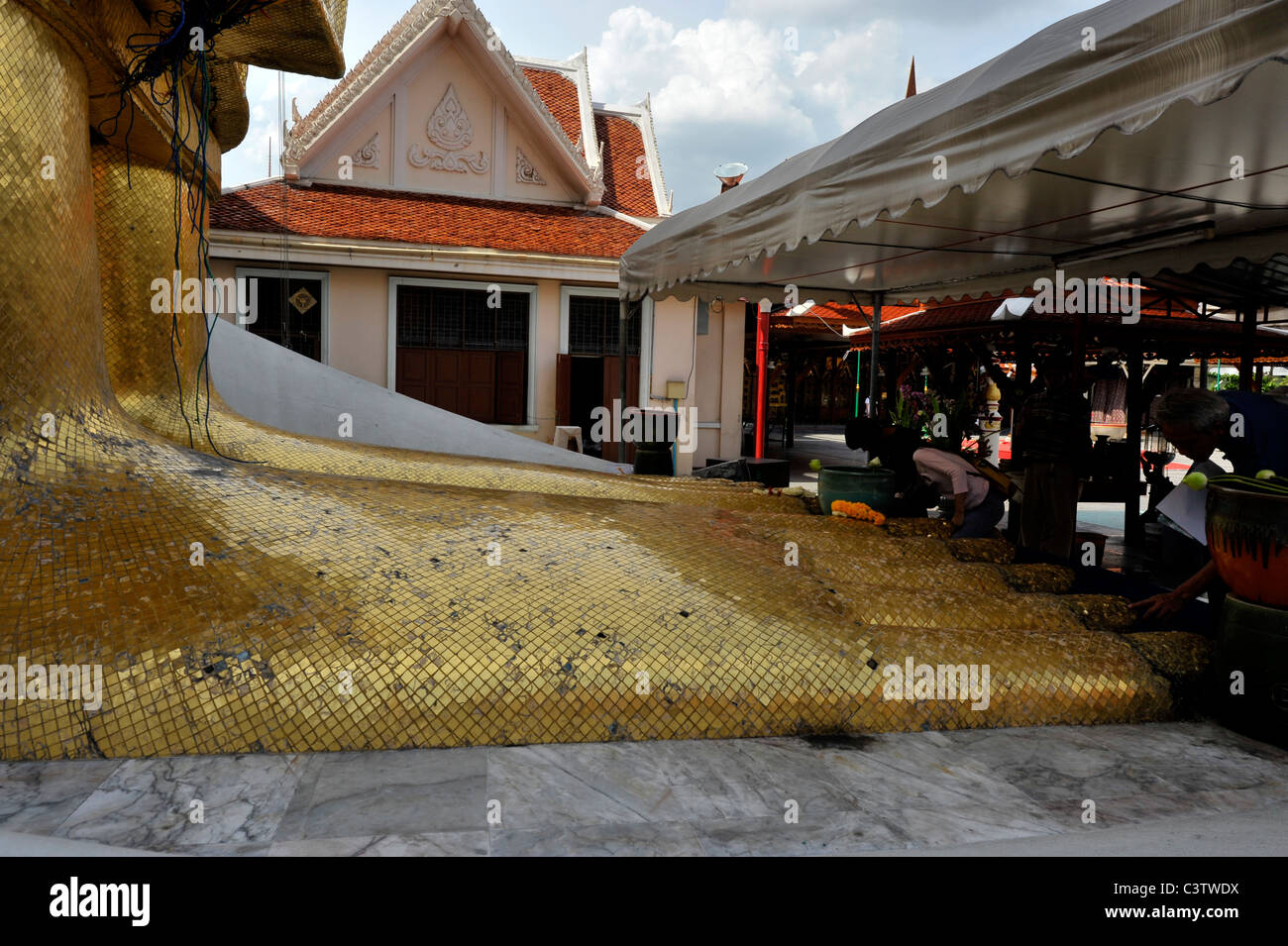 people praying at the feet of the Standing buddha knowns as luang pho at Wat Intharawihan, nakhon district of bangkok, thailand Stock Photo