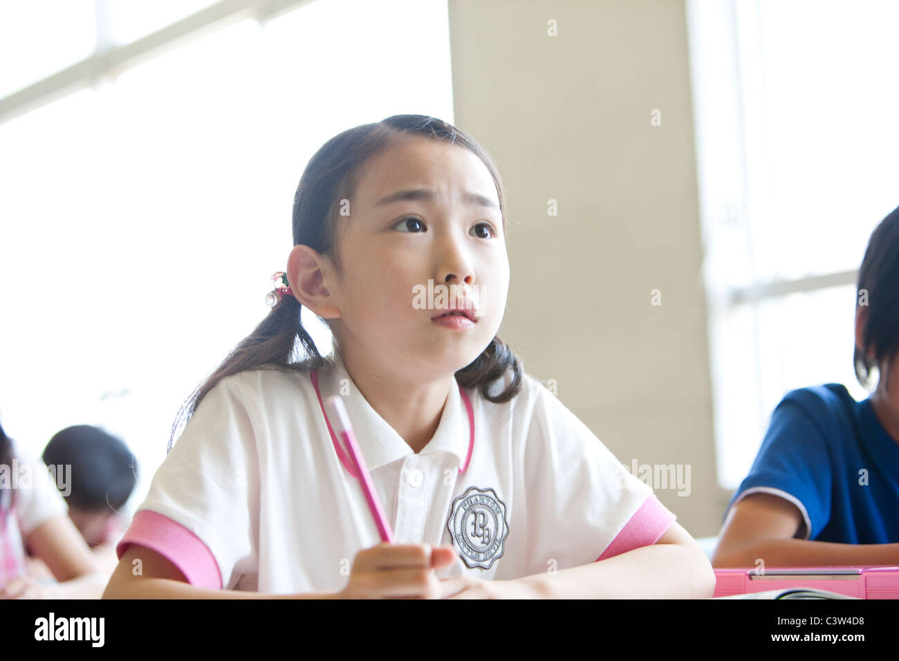 Schoolgirl Listening in Classroom Stock Photo