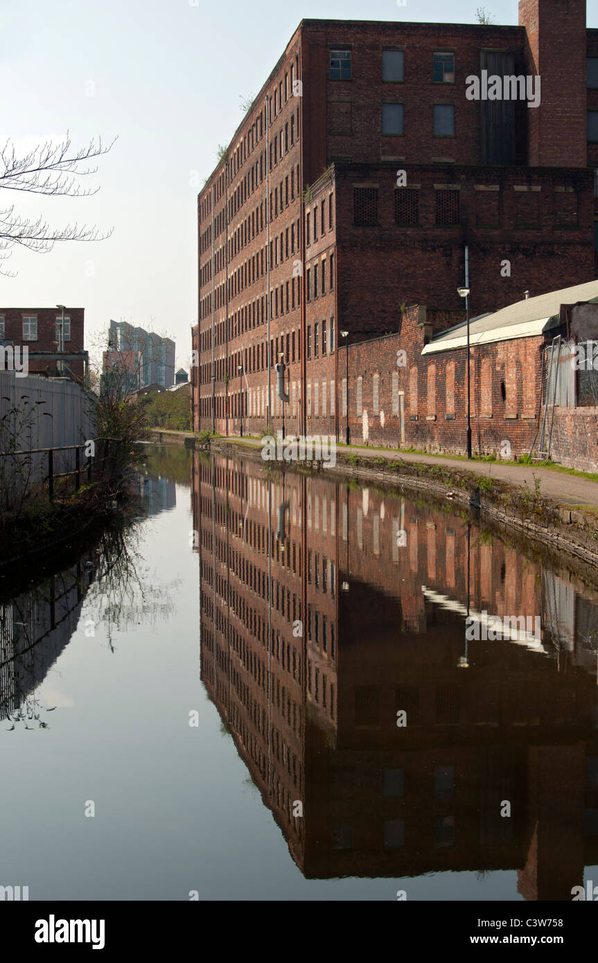 Old cotton mill and the Islington Wharf tower reflected in the Ashton Canal, New Islington