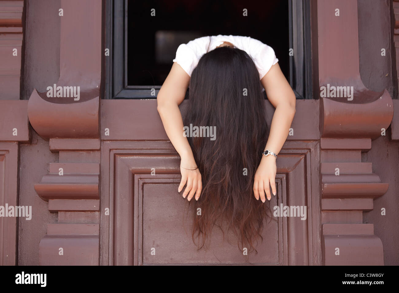 depressed  woman hanging out of wooden window Stock Photo