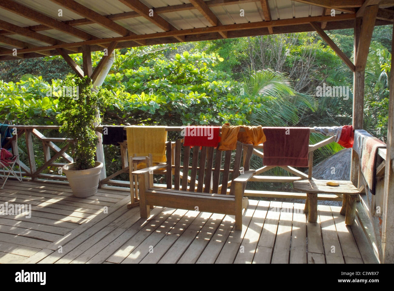 Wooden deck with clothes hanging from the railing. Rustic style. Vegetation on the background Stock Photo