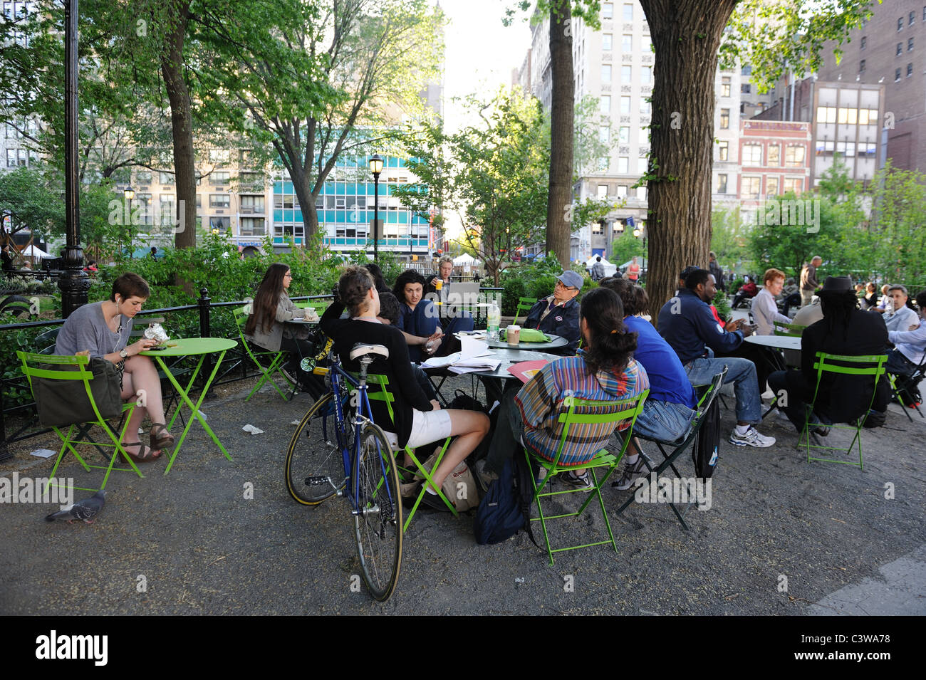 People chat, eat and work at tables and chairs set out at the northern end of Manhattan's Union Square Park. Stock Photo