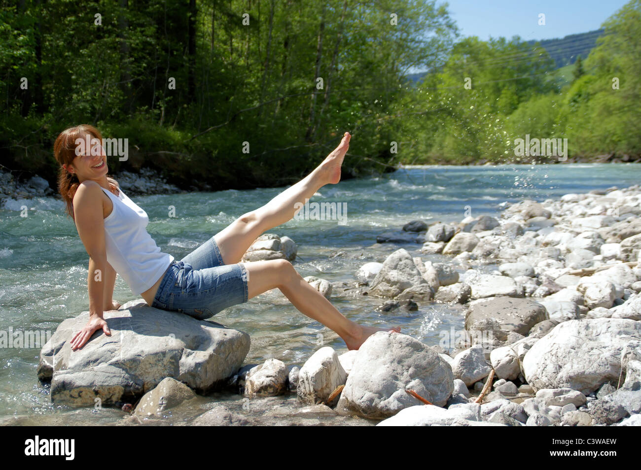 A young, beautiful woman is refreshing in a river. Stock Photo