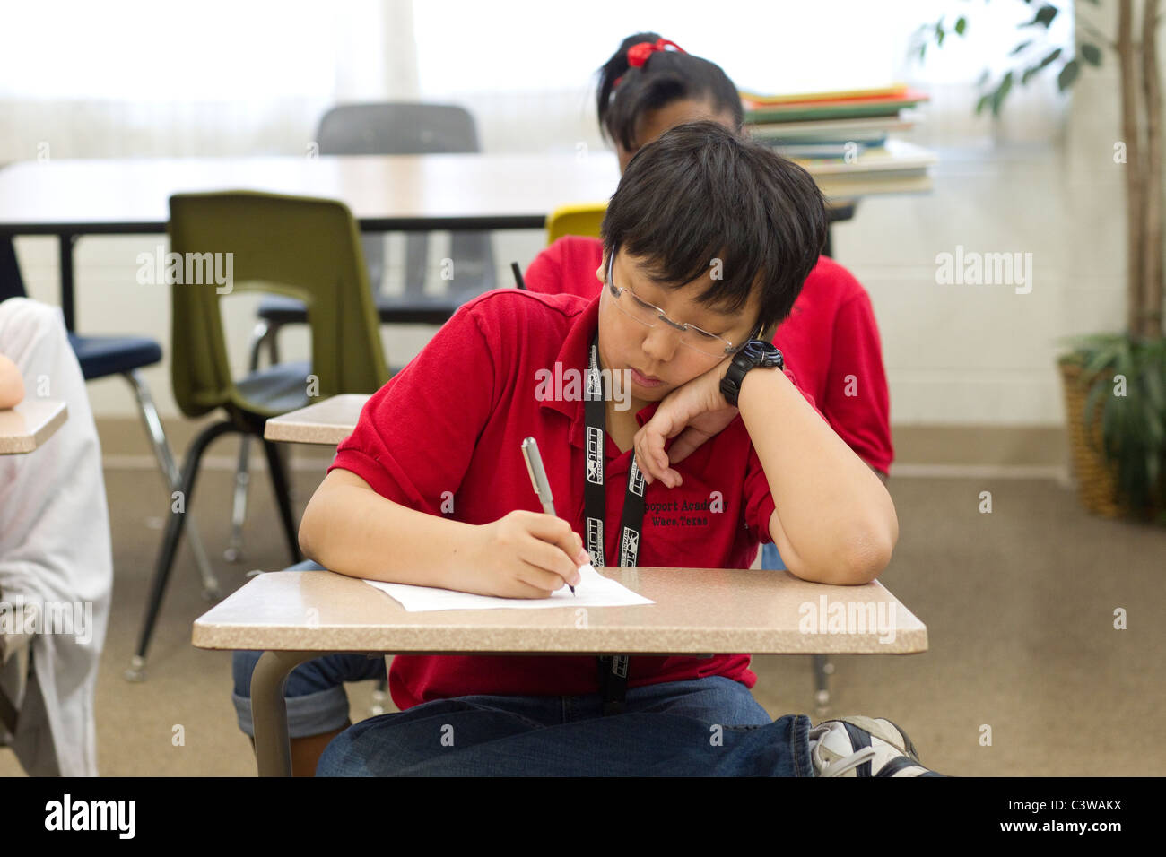 Asian and African-American male and female students take quiz at desks during class at Rapoport Academy public charter school Stock Photo