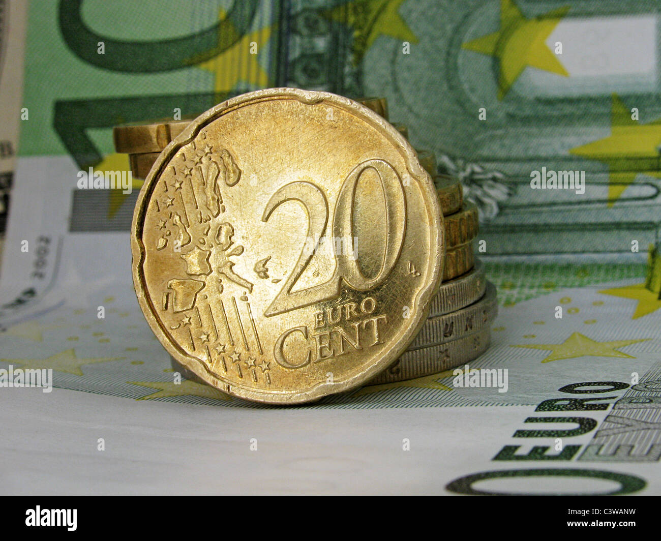 20 cent  coin over pile of other coins on a one hundred euro banknote Stock Photo