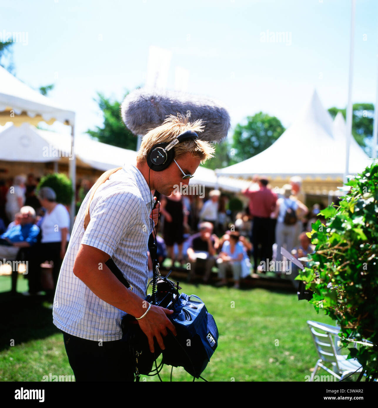 A sound recordist with a boom wearing headphones outside by the marquees working at the Hay Festival, Hay-on-Wye Wales UK  KATHY DEWITT Stock Photo