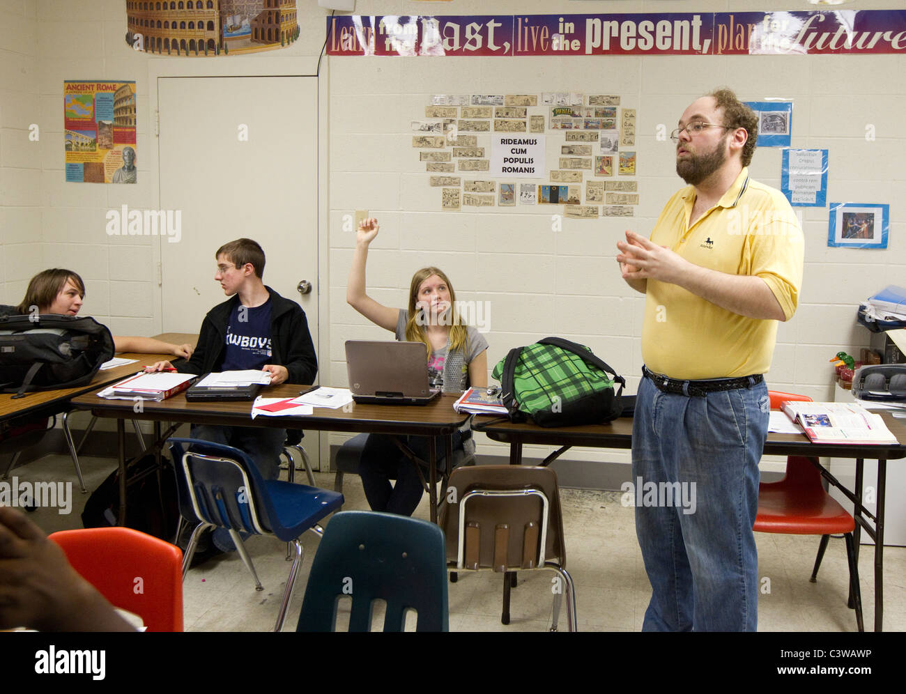 Anglo male teacher conducts class before multiethnic group of students