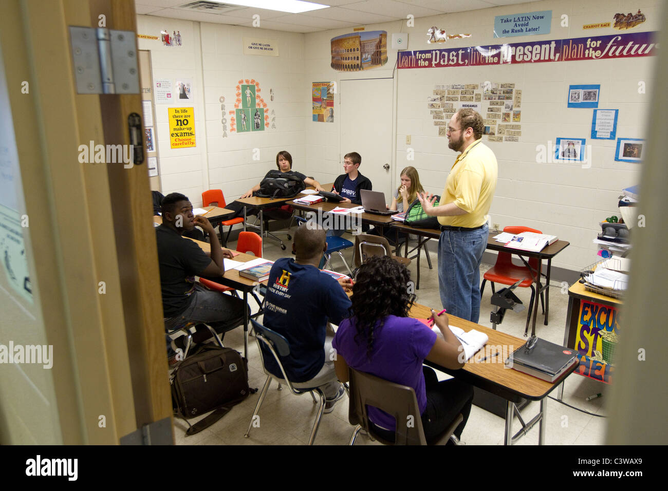 Anglo male teacher conducts class before multiethnic group of students