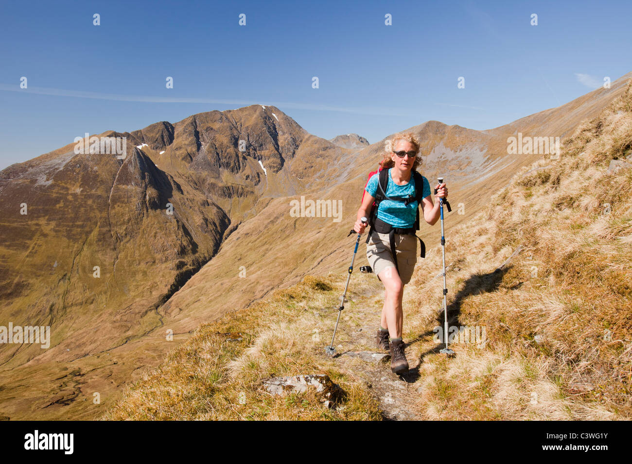 A woman ascending the Mamore mountain range to Am Bodach on a stalkers path, Highlands, Scotland, UK. Stock Photo
