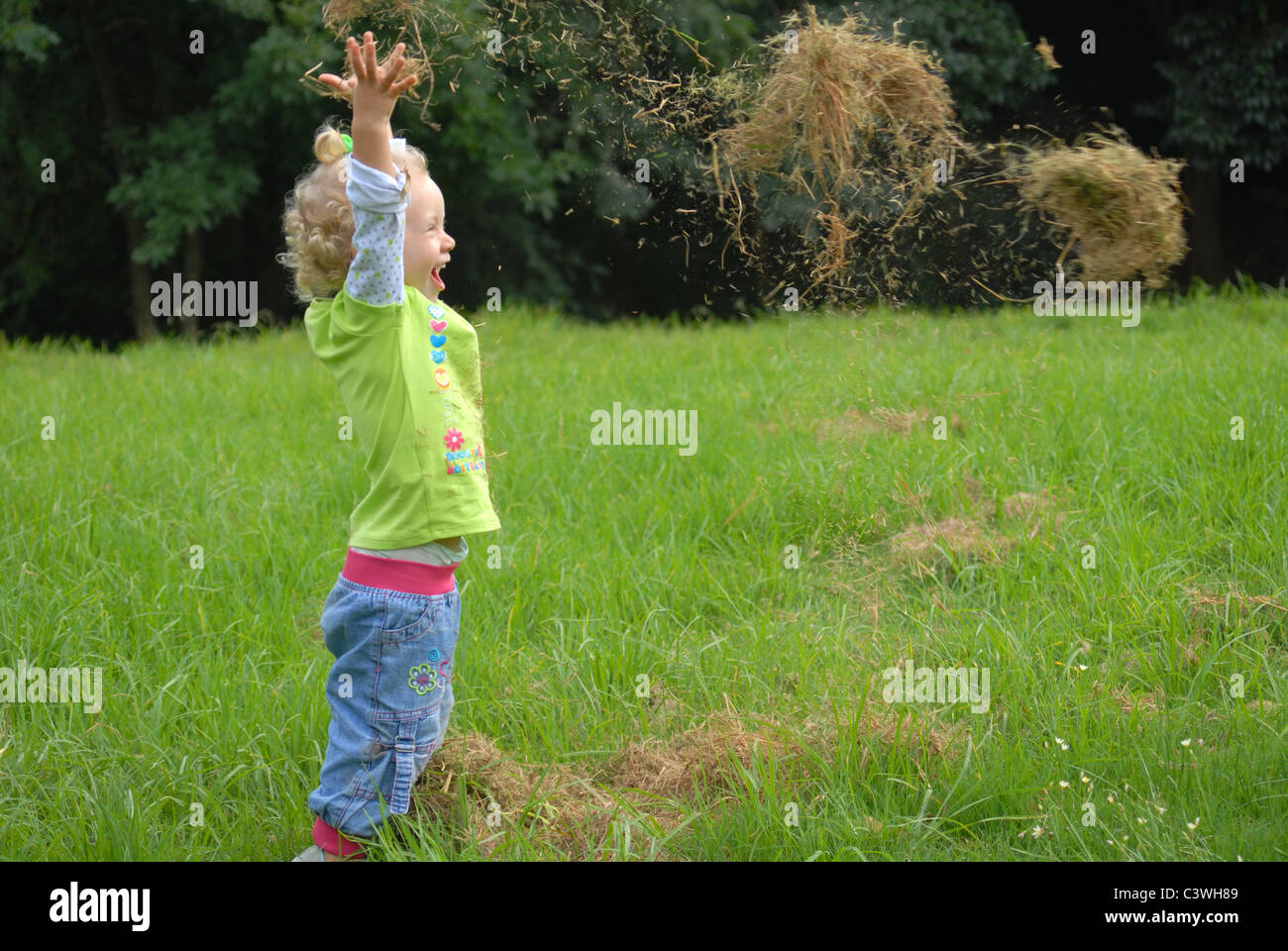 Blondie girl playing with grass on the green field Stock Photo - Alamy