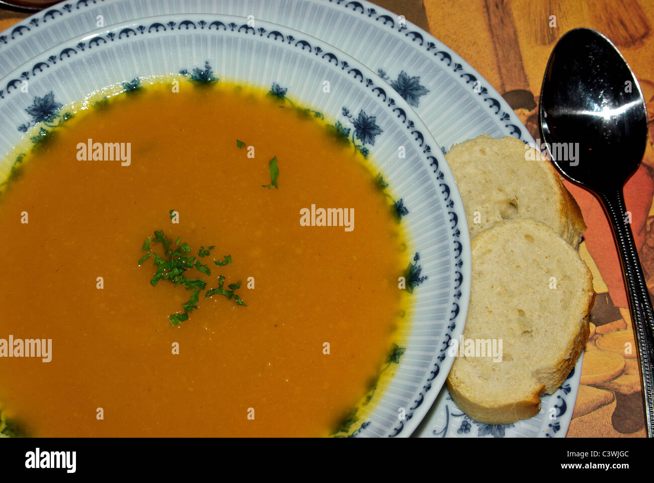 Pumpkin soup chopped parsely garnish in a painted porcelain bowl two slices baguette Stock Photo
