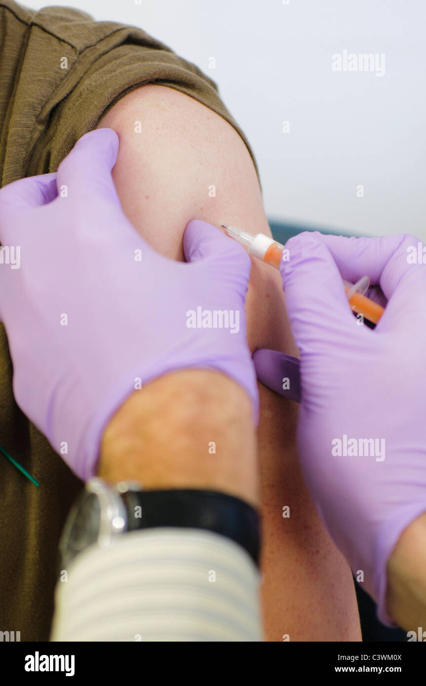 Doctor administers pandemrix vaccine for H1N1 influenza virus (swine flu) to a female patient Stock Photo
