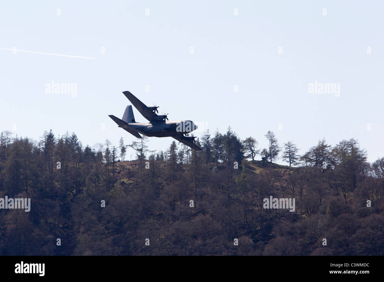 The Lockheed C-130 Hercules  four-engine turboprop military transport low flying over Lake Windermere Claife Hights Stock Photo