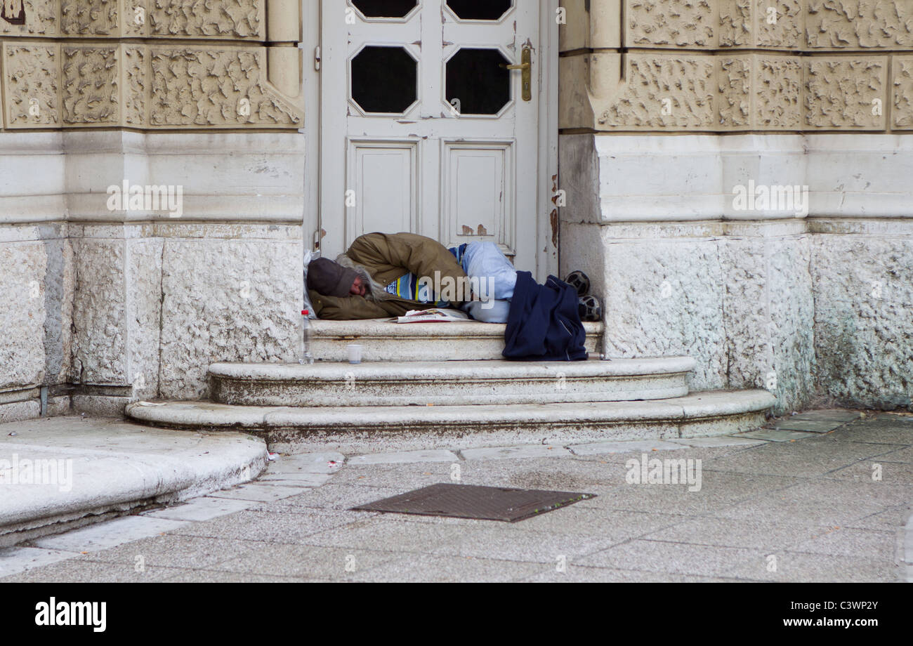 Homeless alcoholic person is sleeping in front of the door. Stock Photo