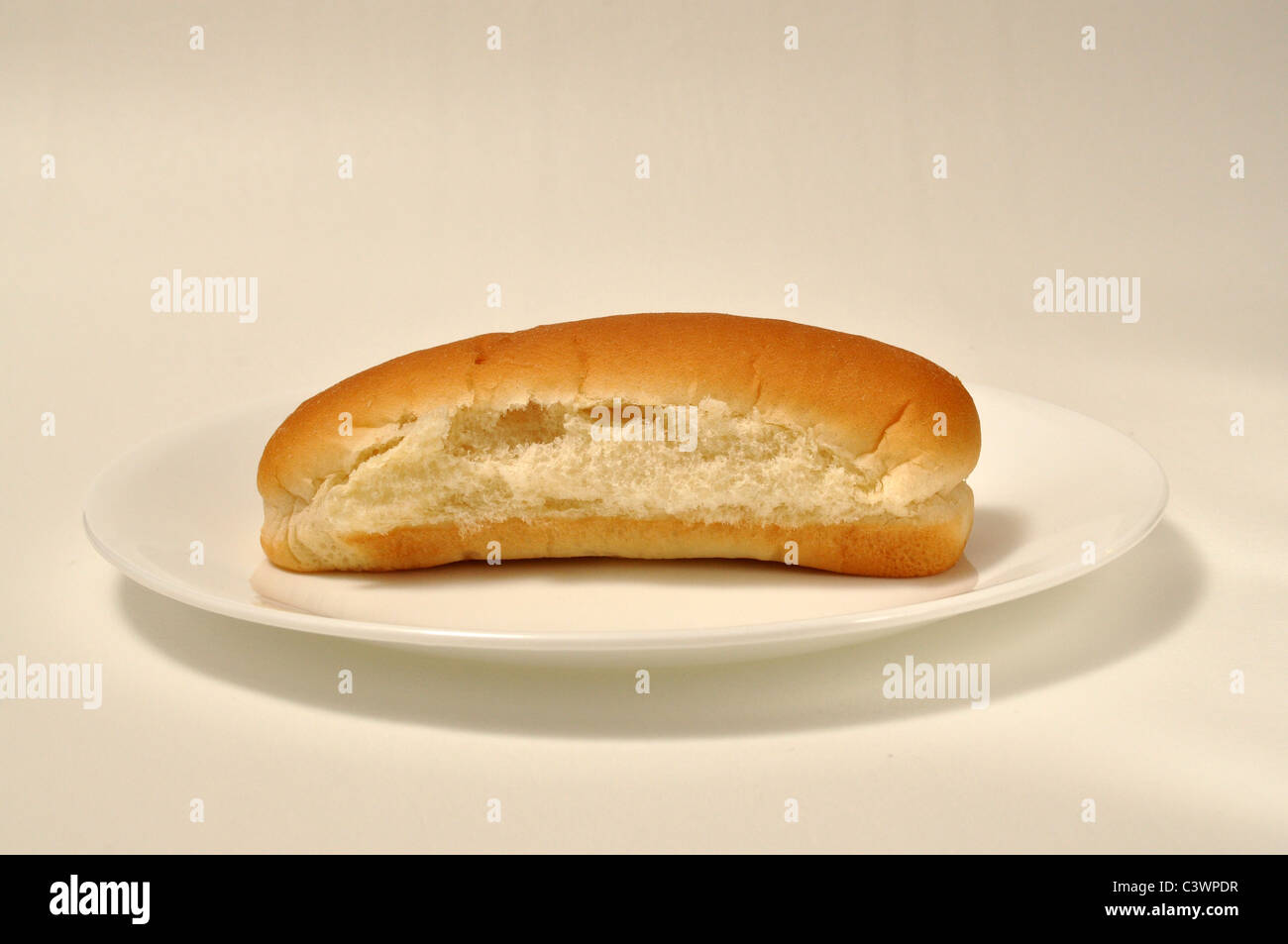 A hot dog bun lays on a plate. Stock Photo