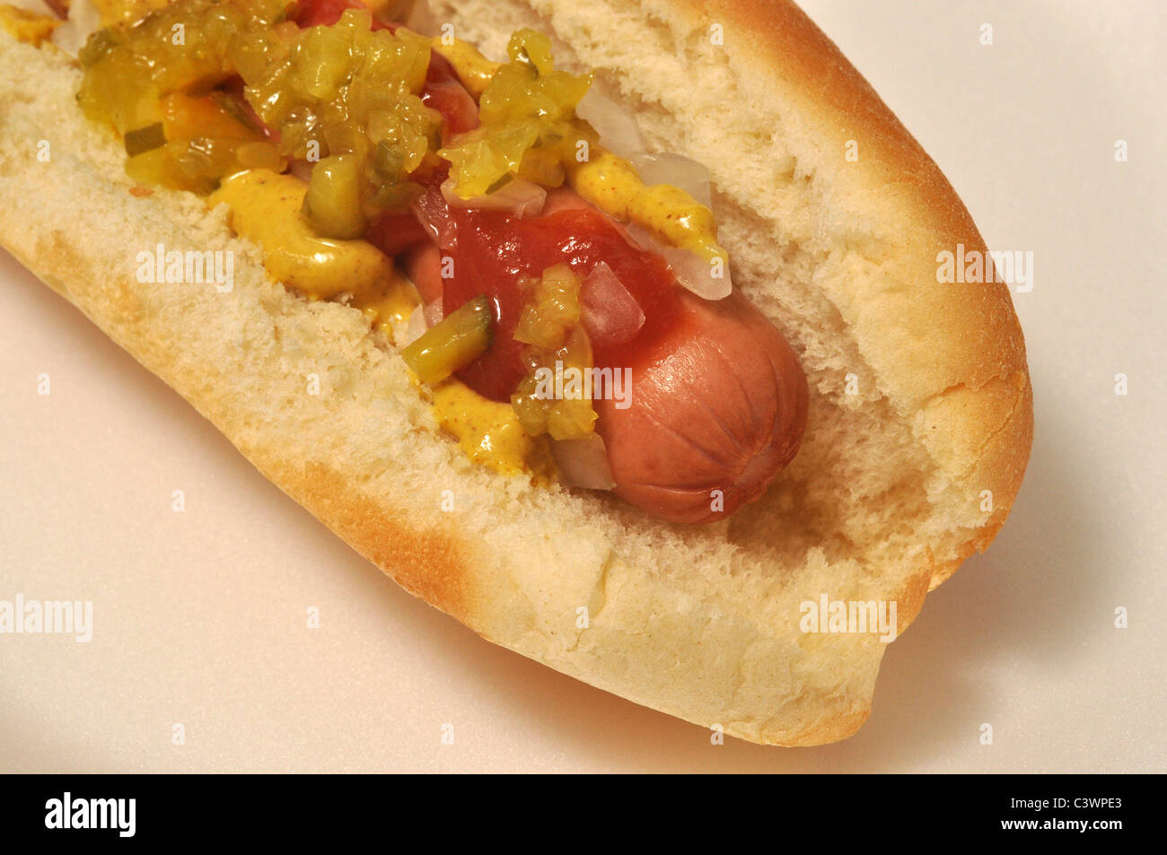 A hot dog with mustard, ketchup, Onion, and relish on a bun. Stock Photo