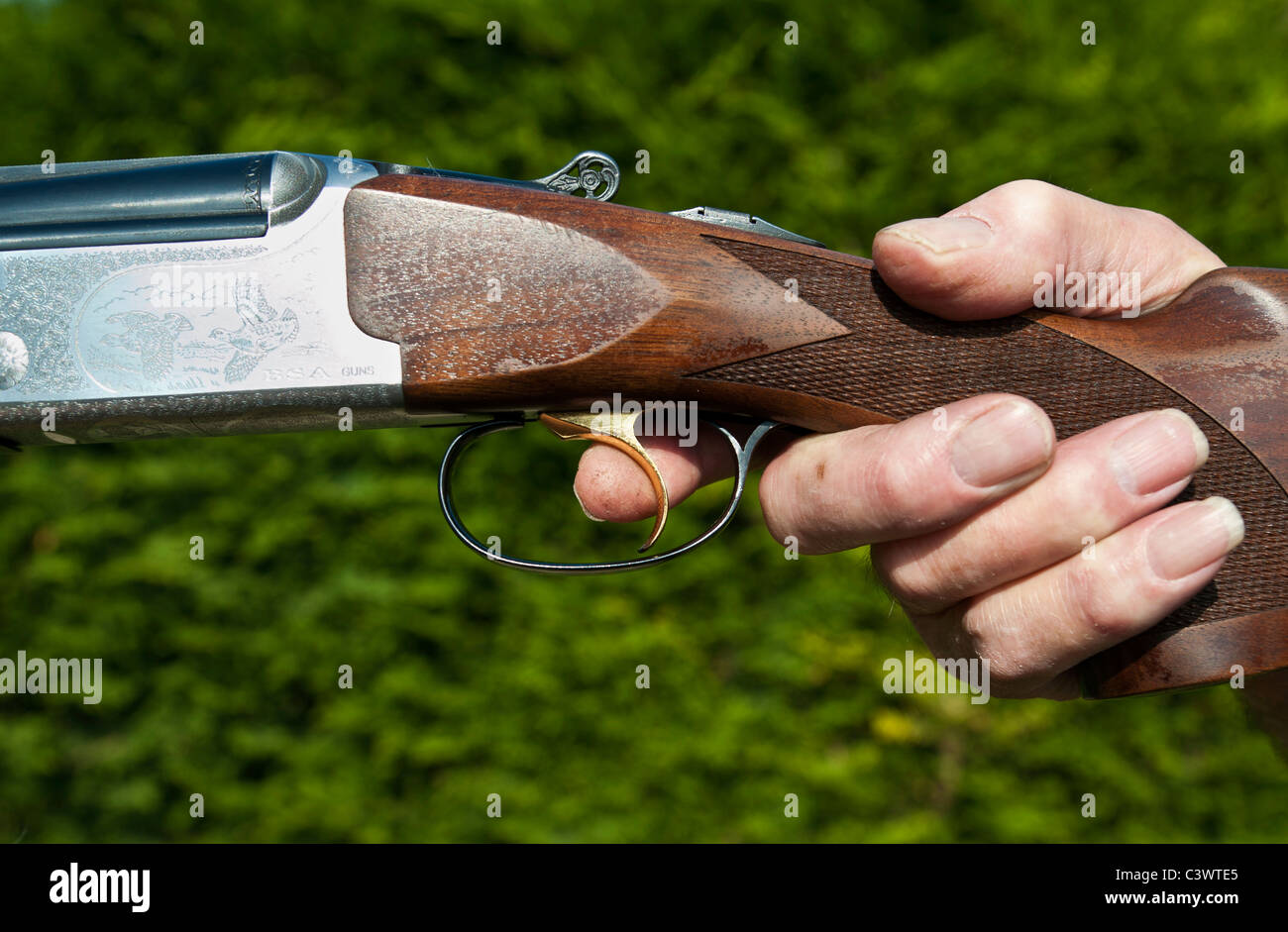 mans hand holding double barrel shotgun with finger on the trigger.landscape format.copy space. Stock Photo