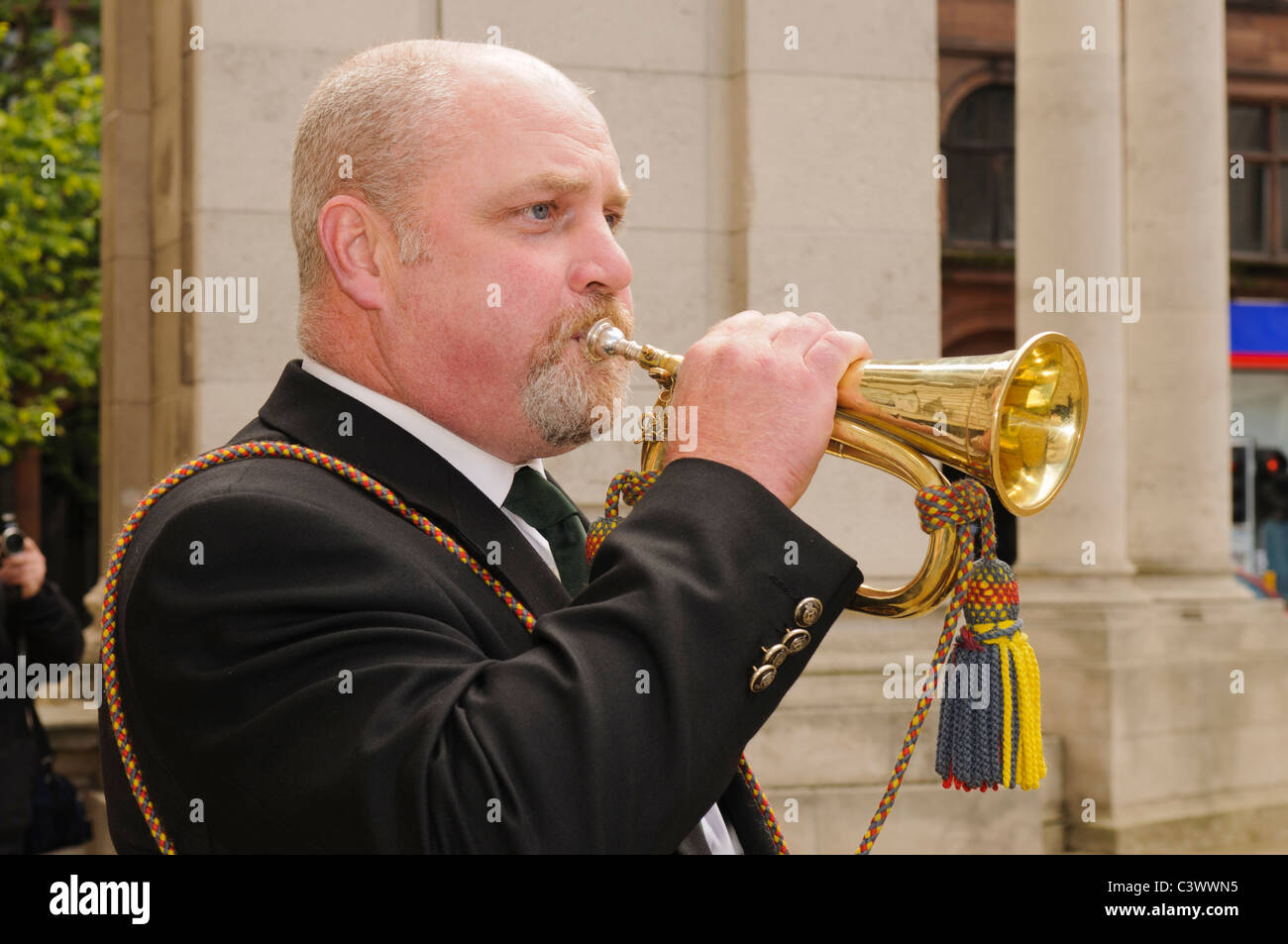 Man plays a brass bugle at a wreathlaying ceremony Stock Photo