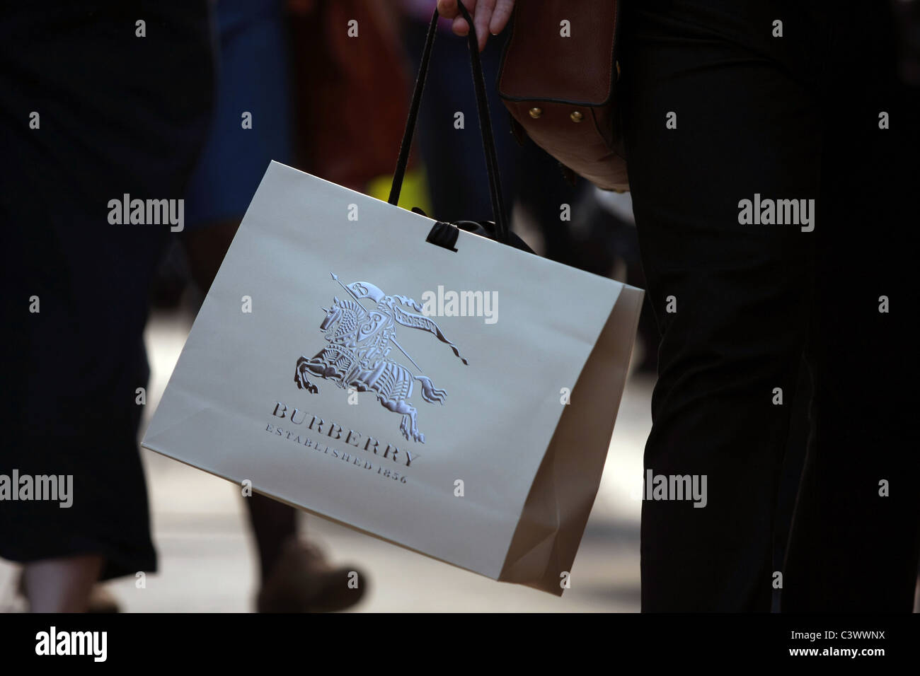 A Burberry shopping bag being carried by its handle Stock Photo