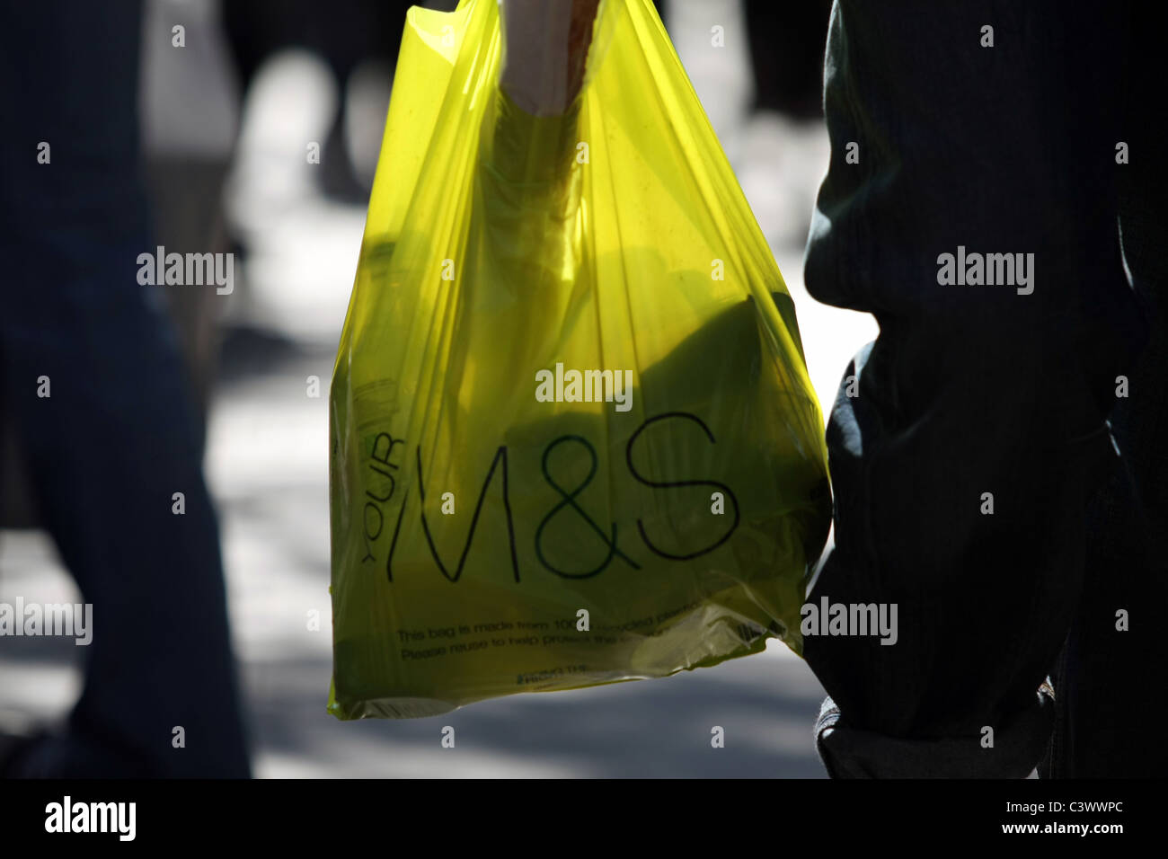 A M&S shopping bag being carried in London with the sun in front of the ...